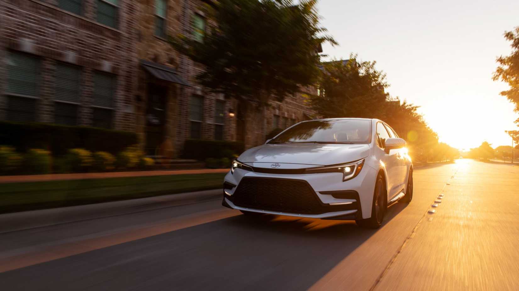 Dynamic front 3/4 thot of a Toyota Corolla Xse Blanche 2025 leading on a country road at sunset.