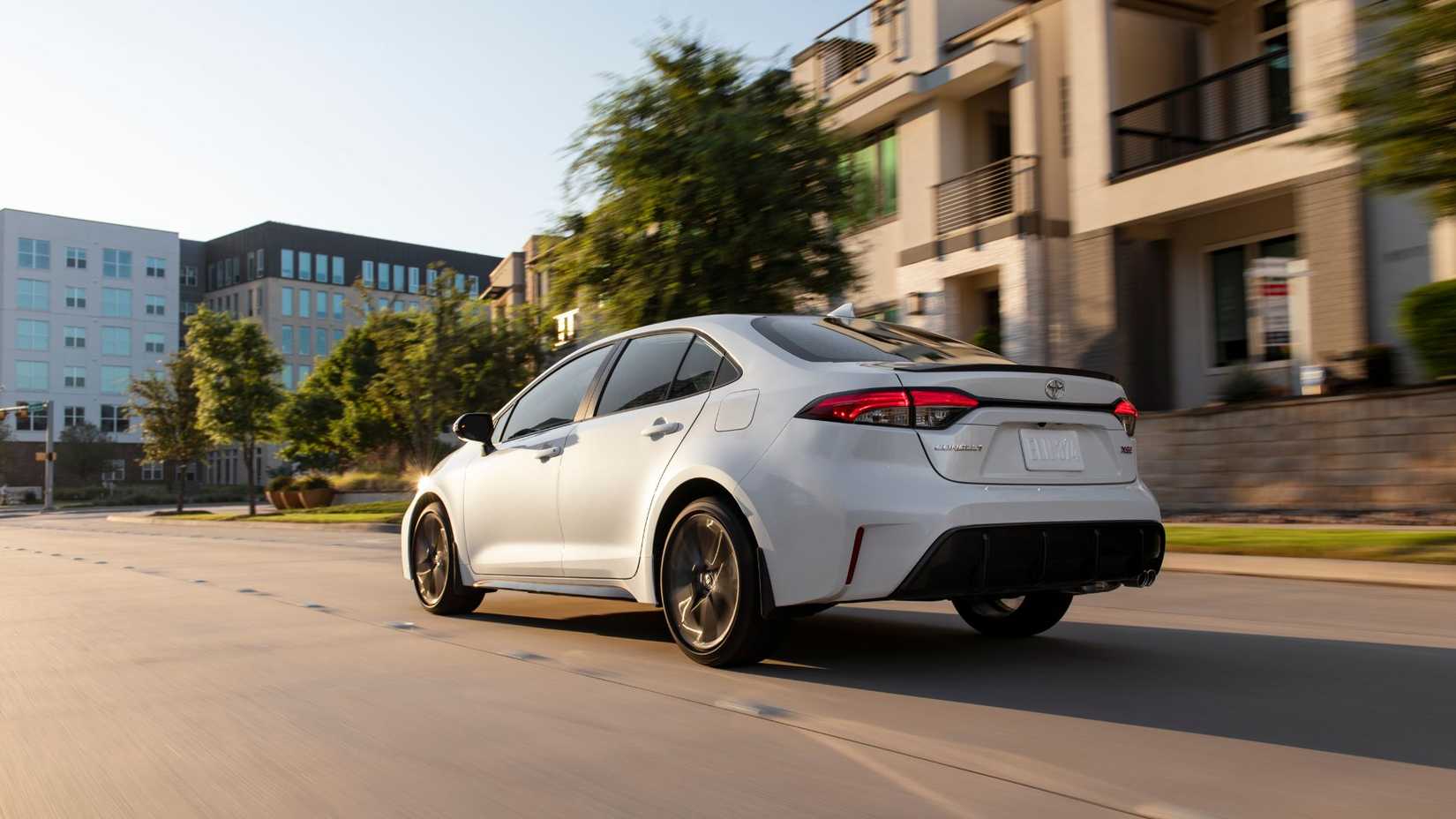 Dynamic rear 3/4 shot of a Toyota Corolla Xse Blanche 2025 drive in a city.
