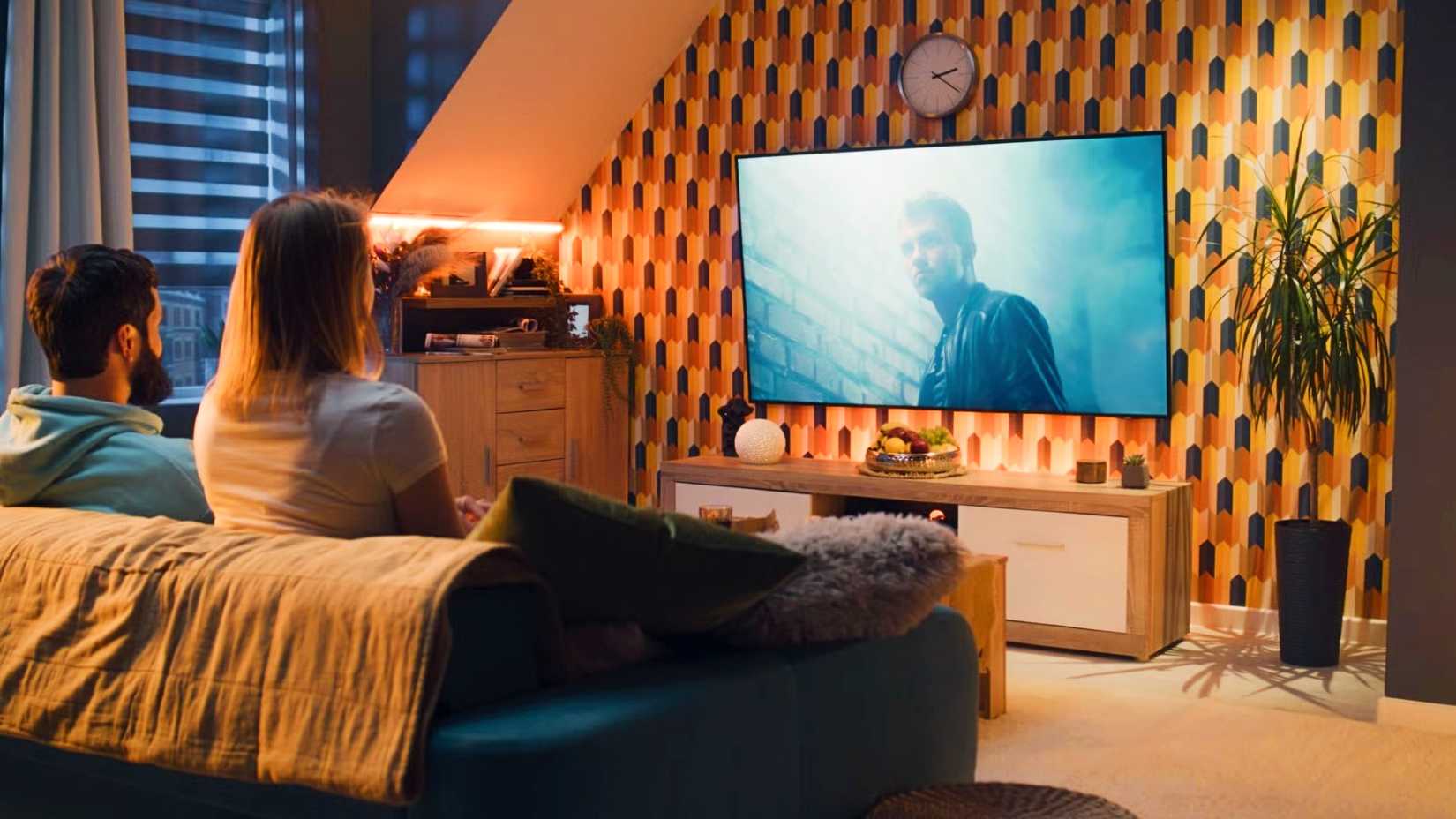 Una pareja sentada en un sofá y viendo una película.