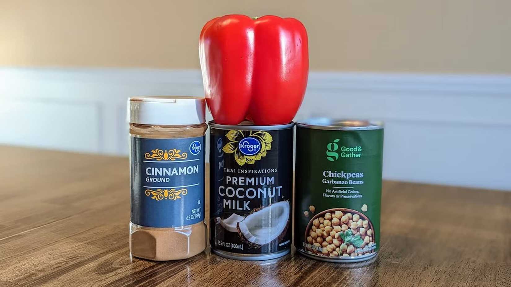 A red pepper on top of a cinnamon shaker and two cans.
