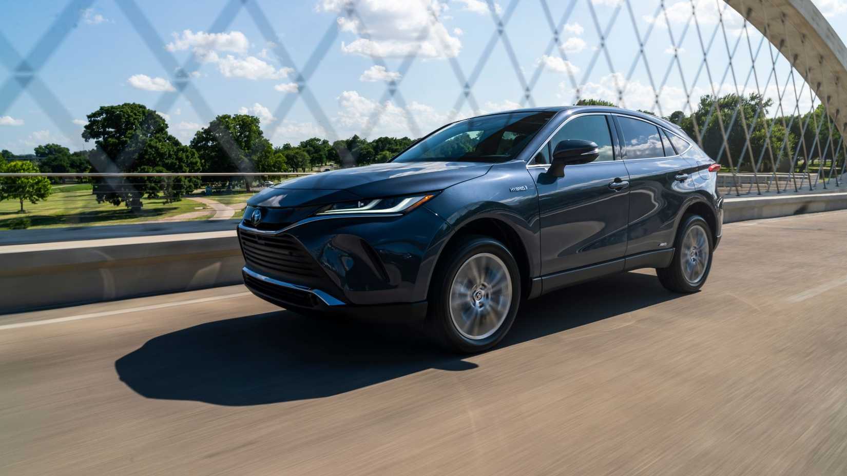 Dynamic front 3/4 shot of a blue 2021 Toyota Venza driving over a bridge.