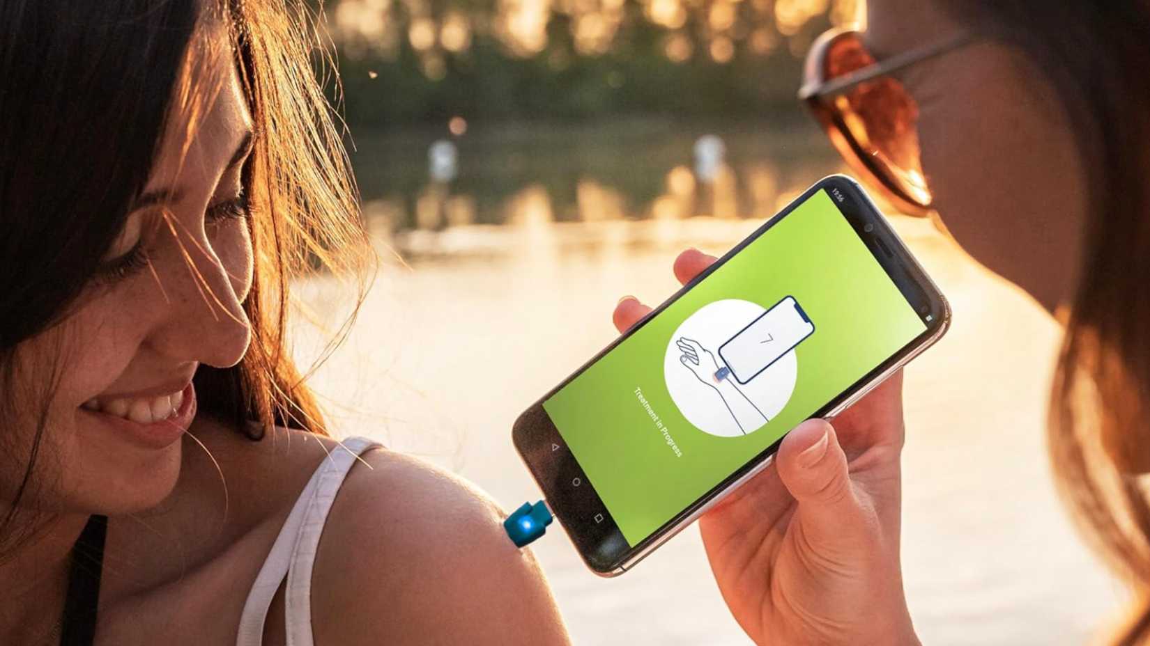 Woman holding a heat it bug healer USB stick on a phone.