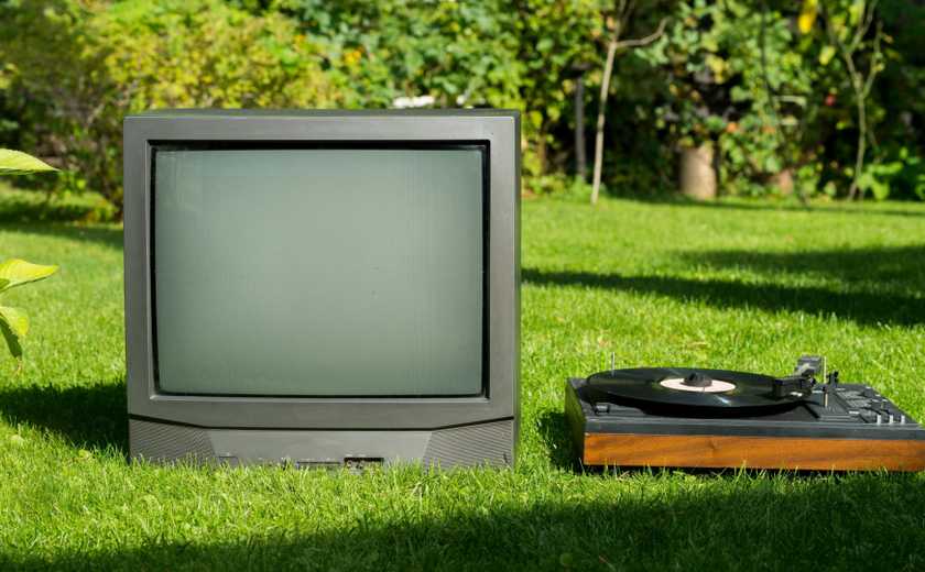 A vintage TV and record player next to each other on the lawn.