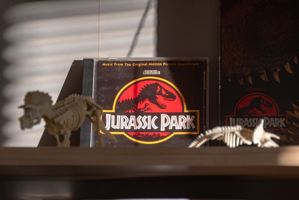 The Jurassic Park soundtrack on a shelf with some dinosaur skeleton figures.