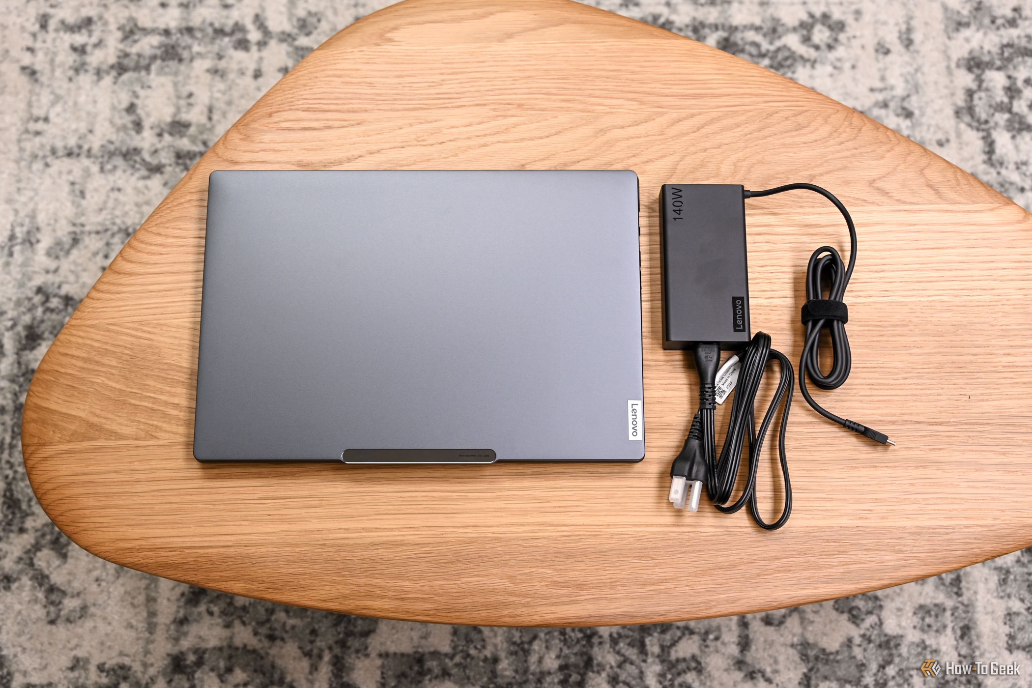 The closed Lenovo Slim Pro 9i 14 Gen 8 with its charger.