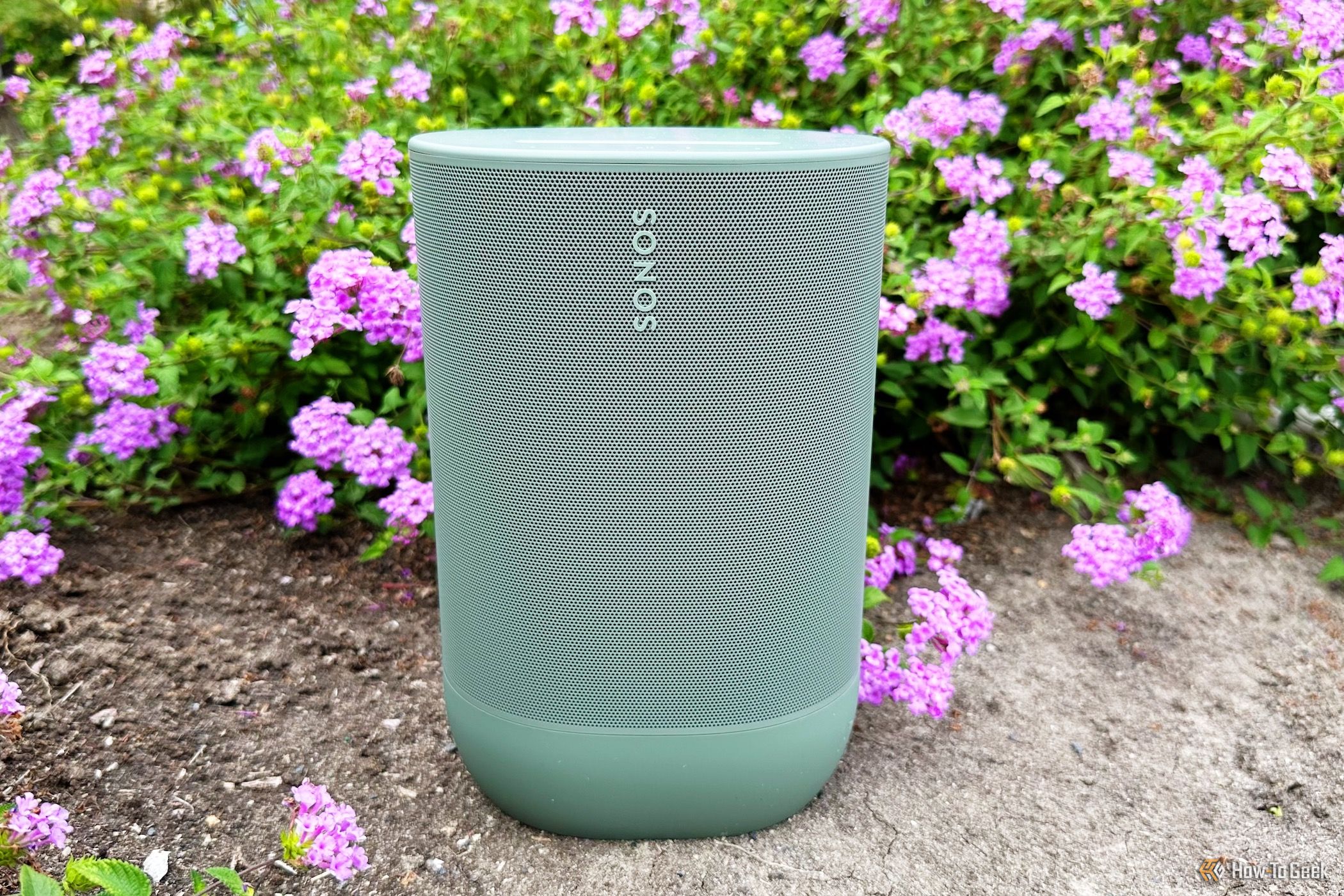 Sonos Move 2 sitting on a dirt patch in front of flowers