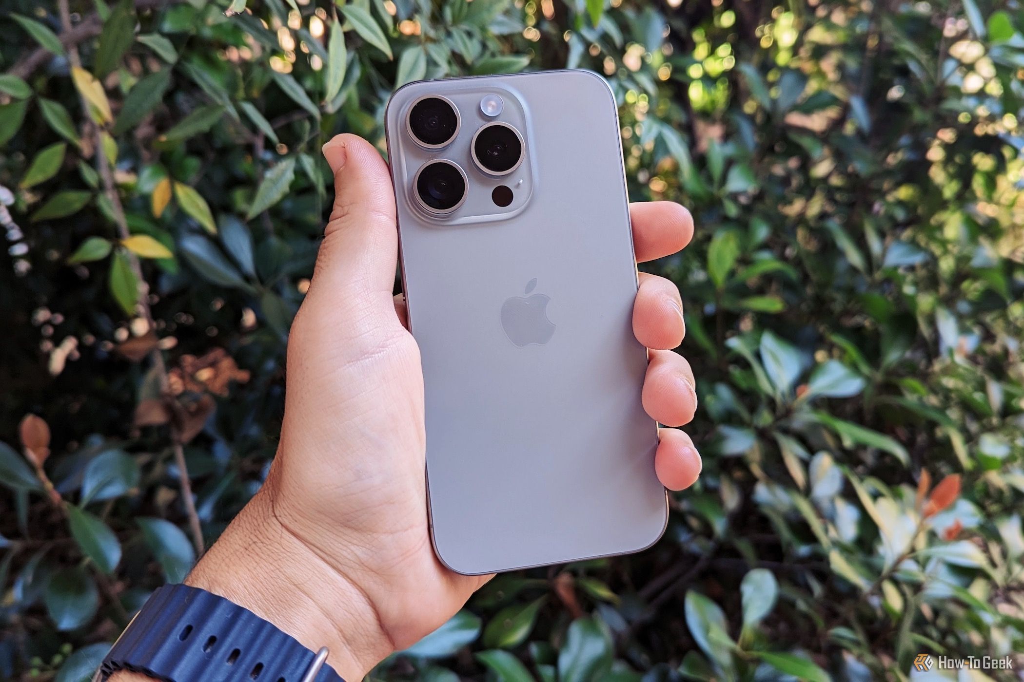 A hand holding the Apple iPhone 15 Pro, showing the back glass.