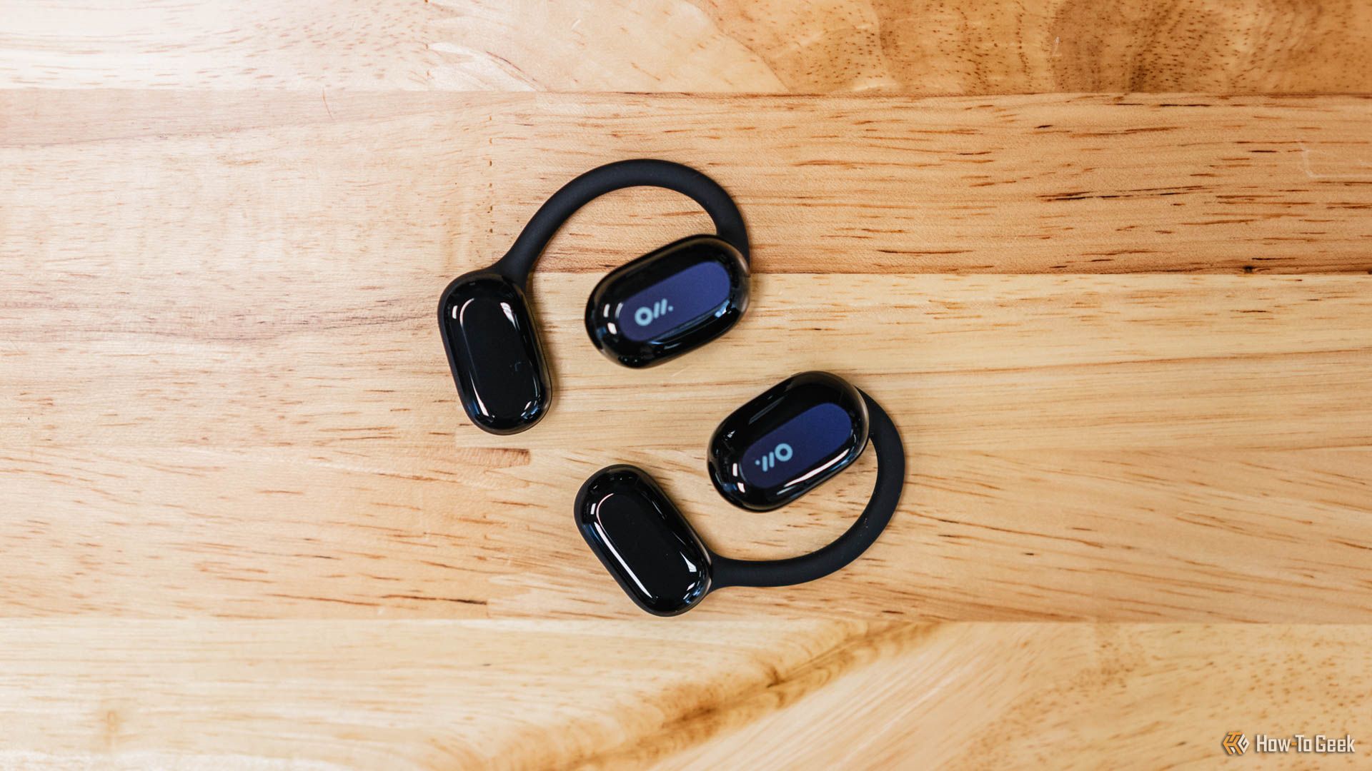 The Oladance Open-Ear Headphones on a wooden table.