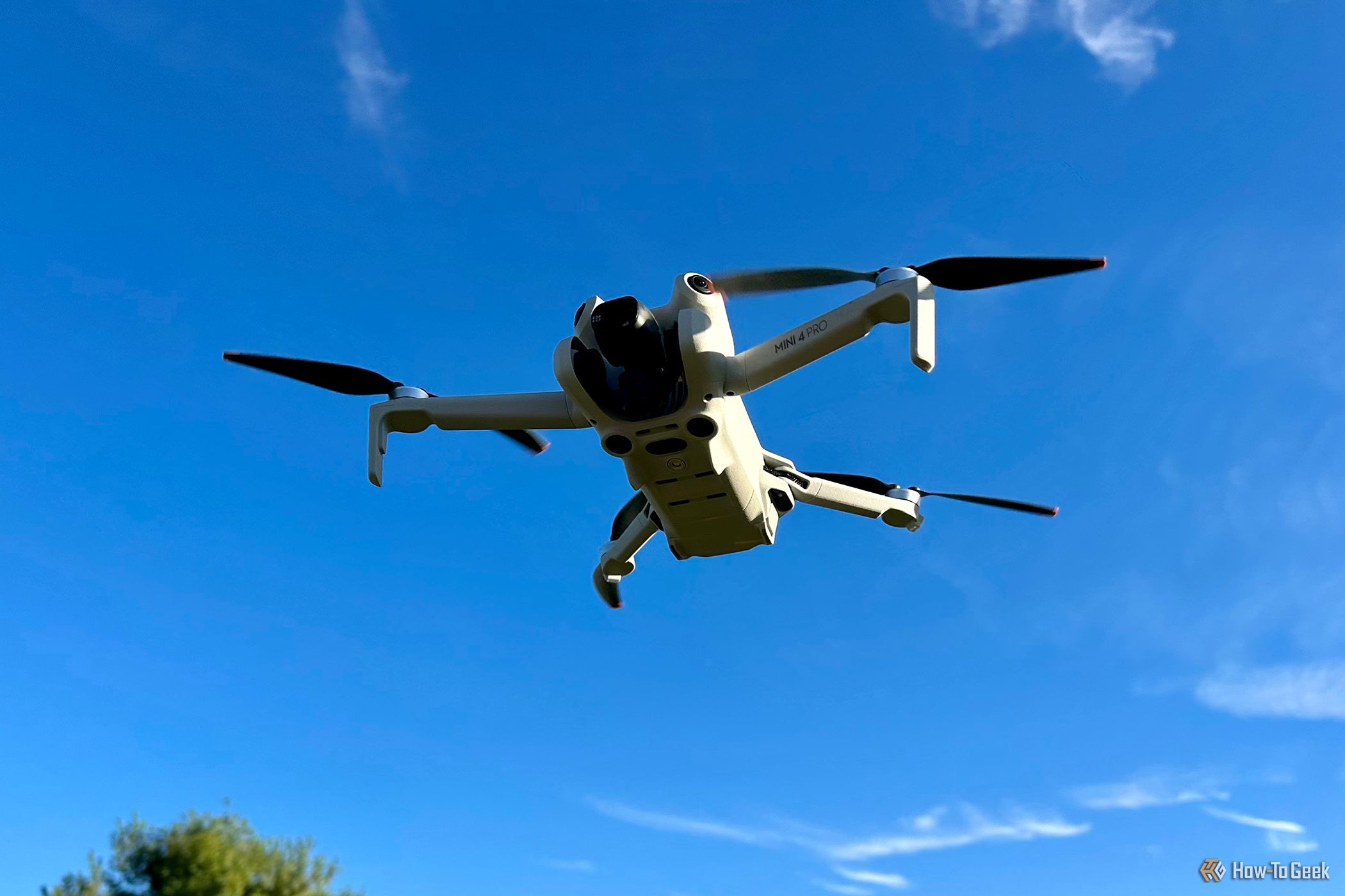 DJI Mini 4 Pro shown flying against a blue sky