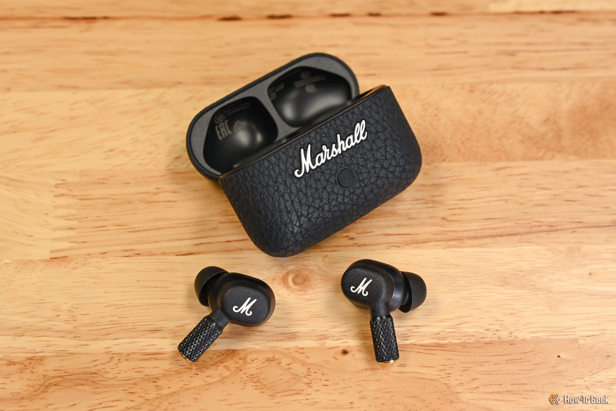 A pair of Marshall Motif II ANC earbuds laid out in front of the case-1