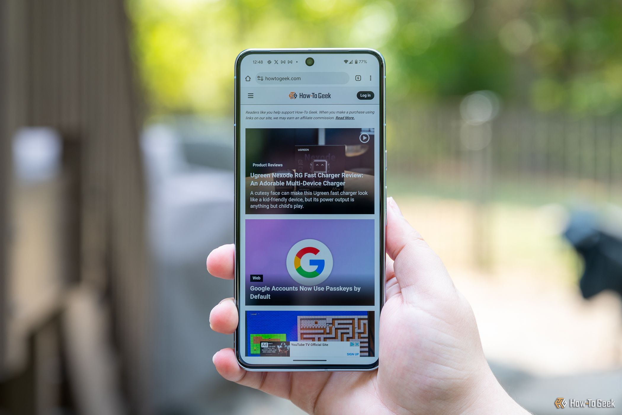 Person holding the Google Pixel 8 Pro showing the How-To Geek website