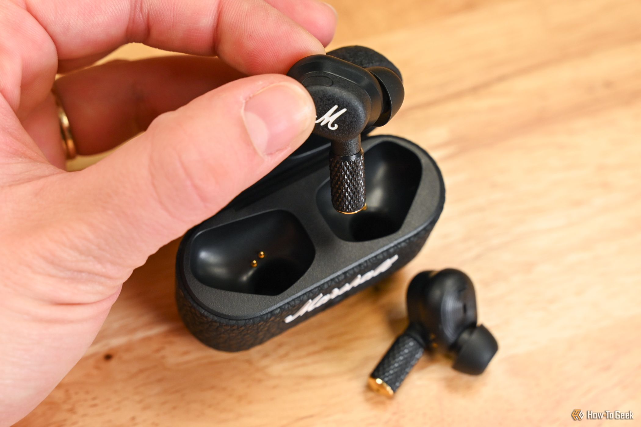 Person putting Marshall Motif II ANC earbuds in the case