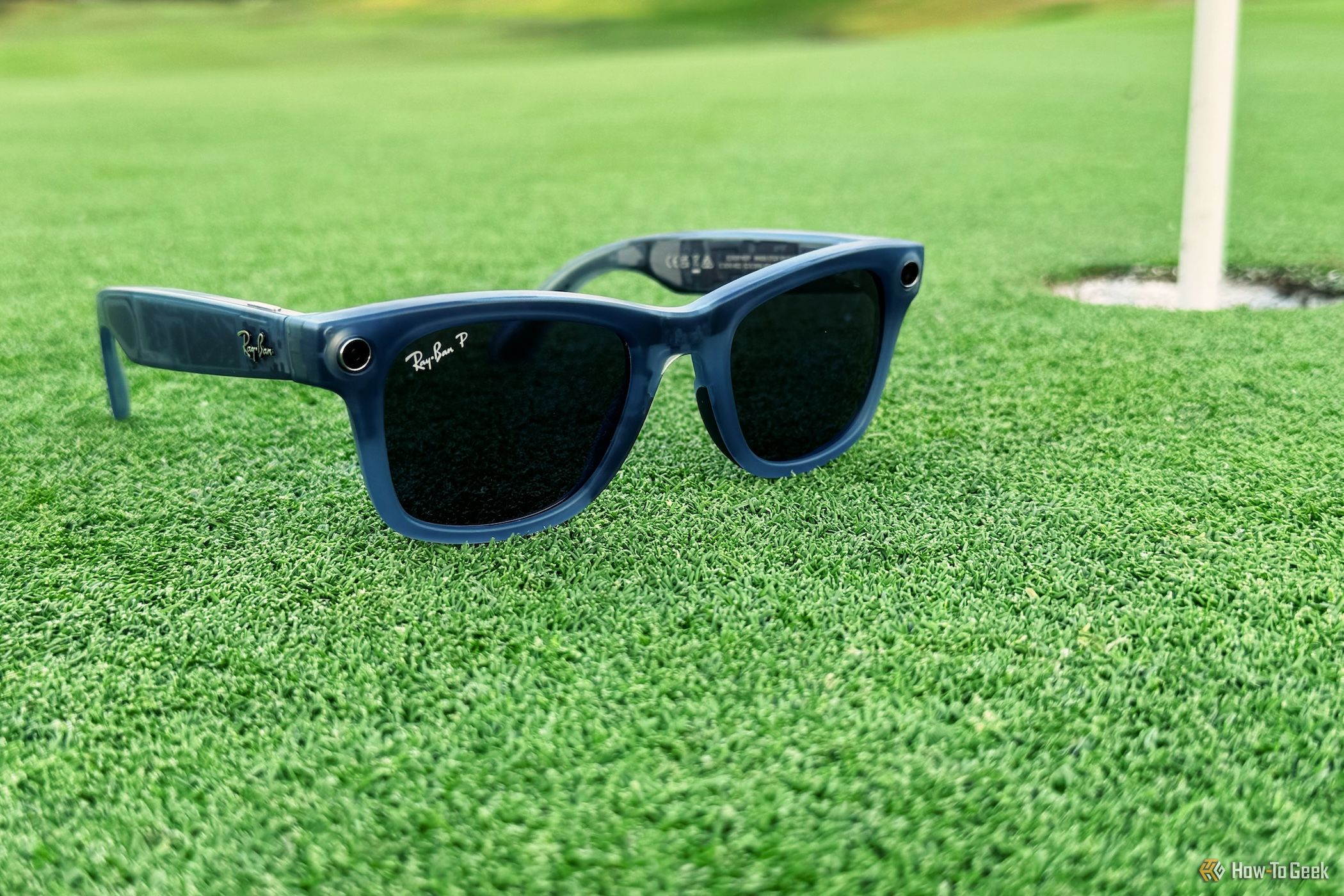 Ray-Ban Meta Smart Glasses unfolded on grass next to golf hole