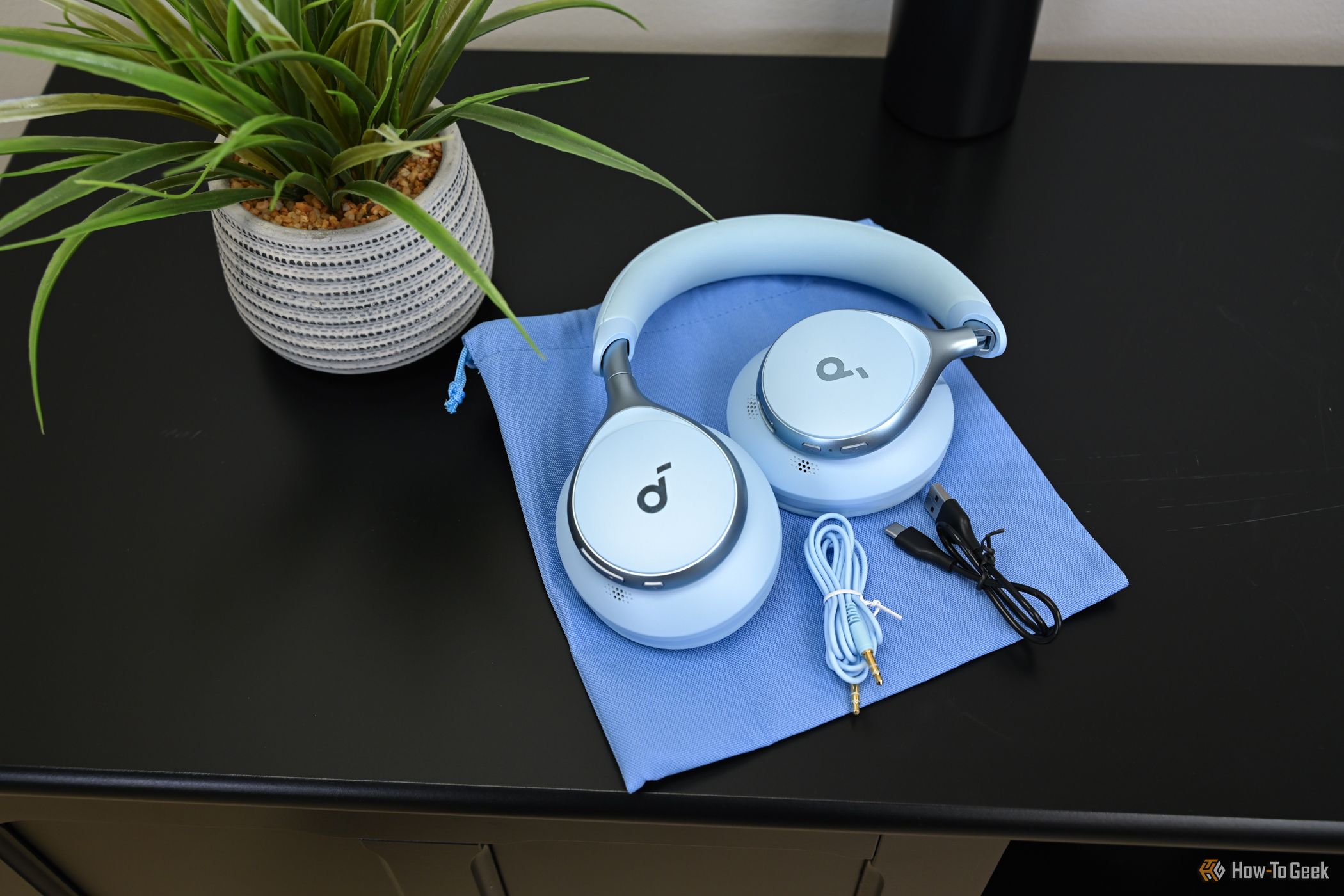Soundcore Space One headphones on a table with charging wire and AUX cable