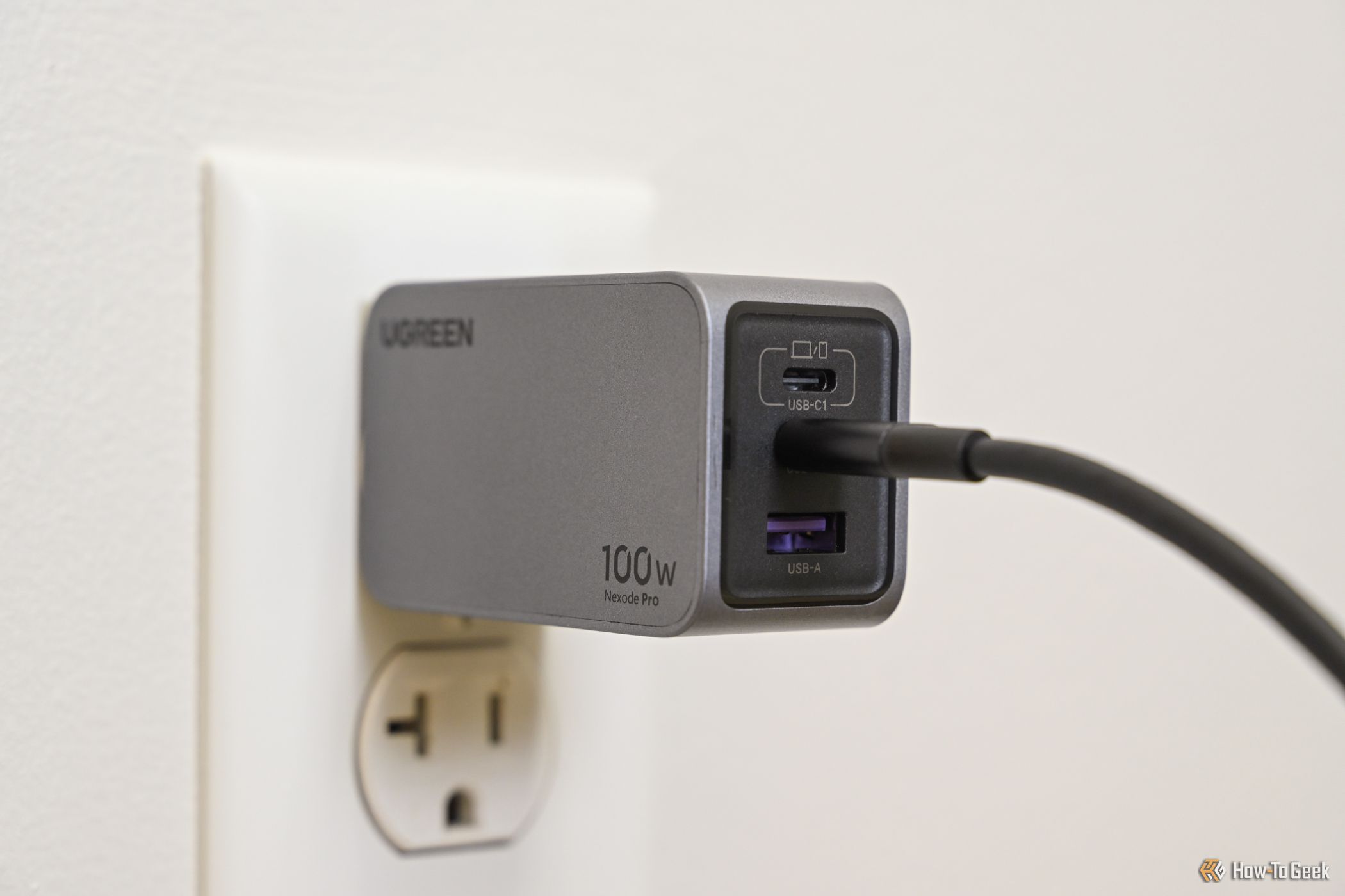 The Ugreen Nexode Pro 100W USB C Wall Charger plugged into an outlet