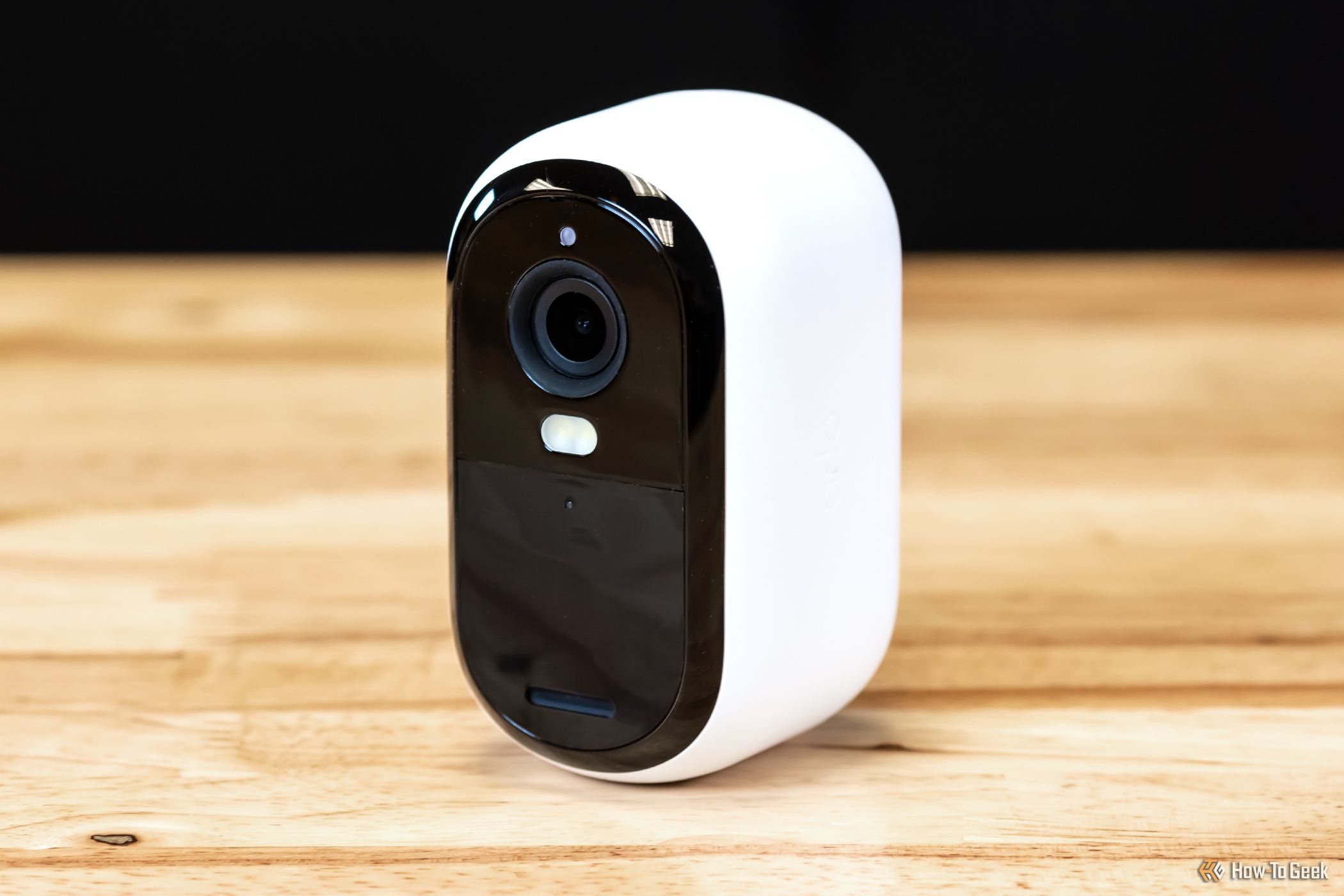 Arlo Essential 2K outdoor security camera on a wood table. 