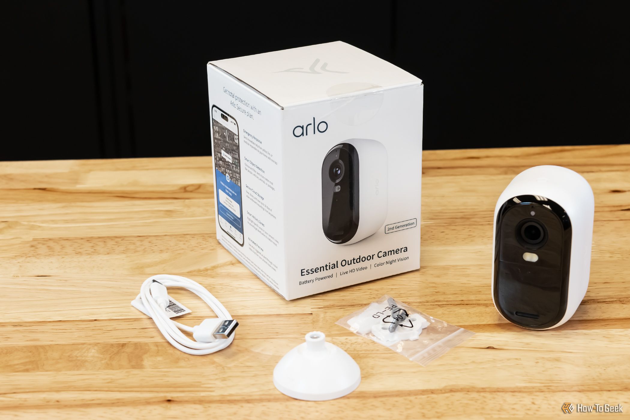 An Arlo Essential Outdoor Camera on a table with its accessories and box. 