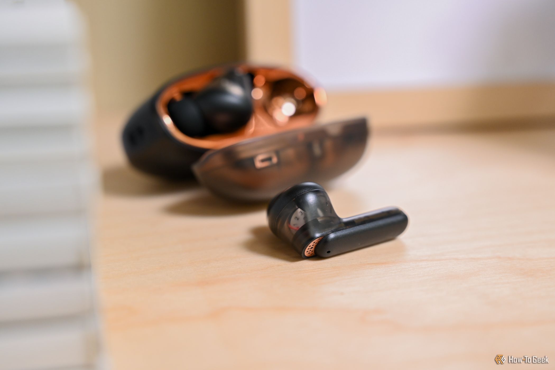 One Creative Aurvana Ace 2 earbud in front of its case
