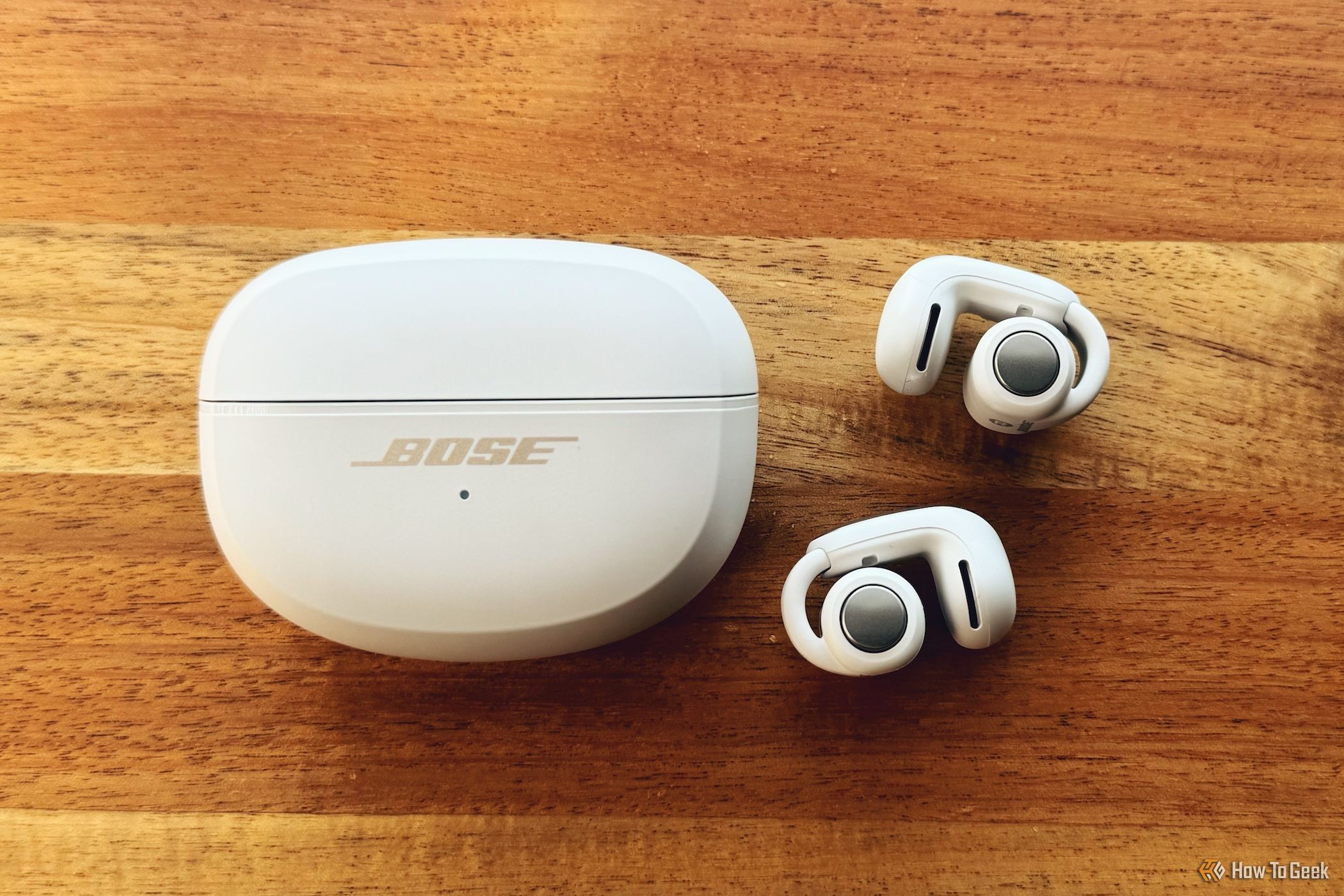 Bose Ultra Open Earbuds lying next to closed case
