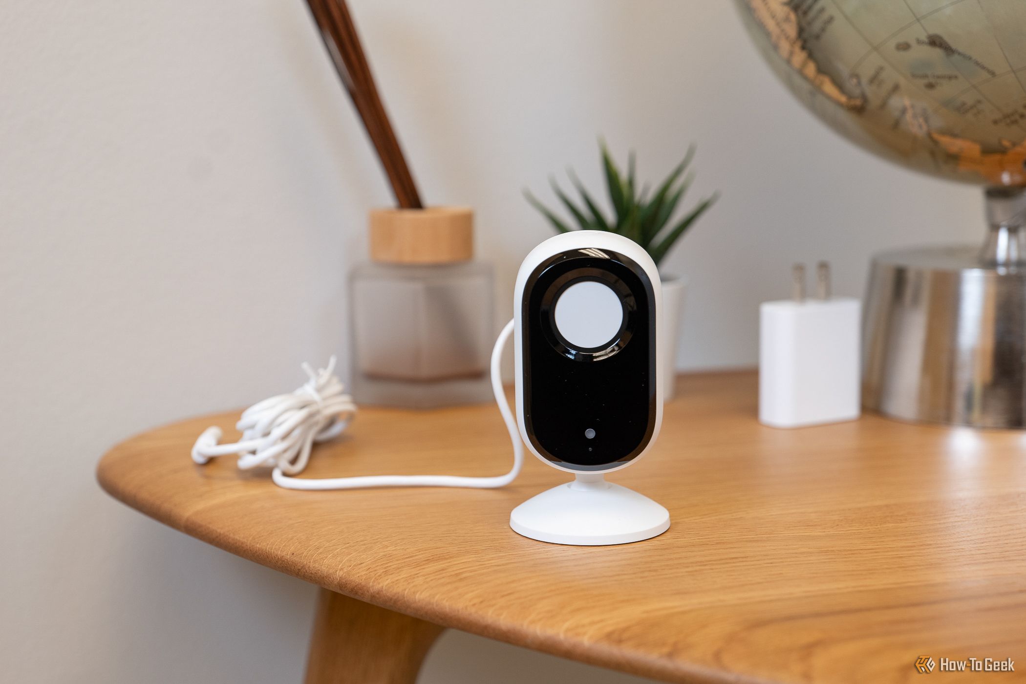 The Arlo Essential Indoor Cam (2K) placed on a table with the privacy shutter covering the lens.