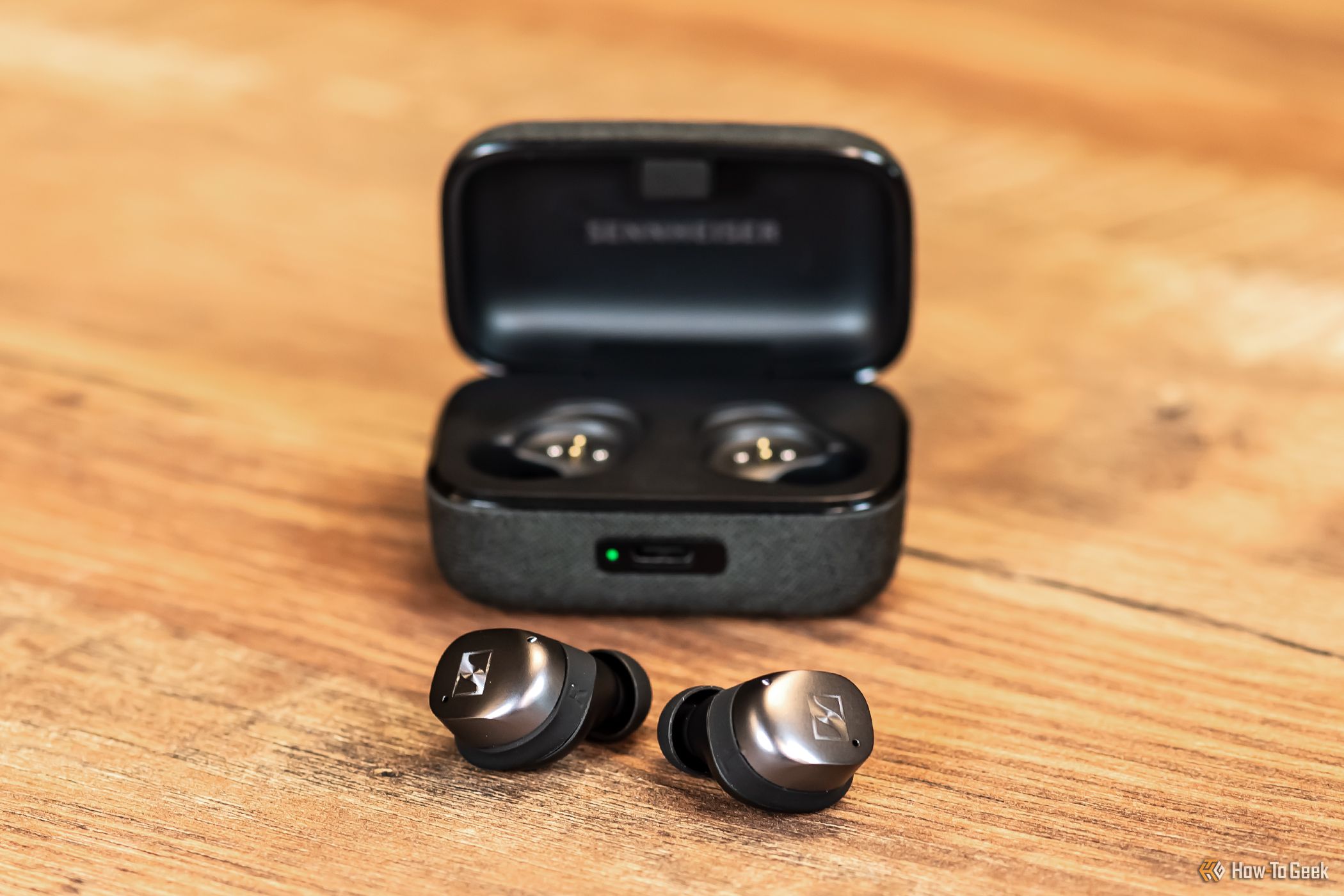 A pair of Sennheiser Momentum True Wireless 4 earbuds in front of their case