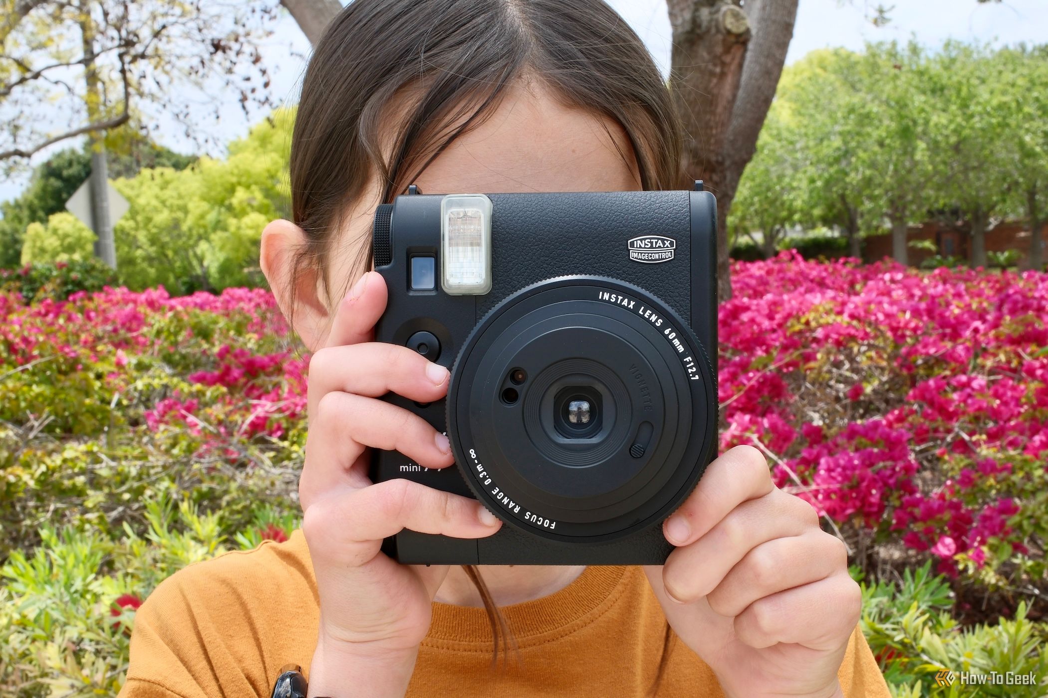 A girl holding the Fujifilm Instax Mini 99 about to take a photo