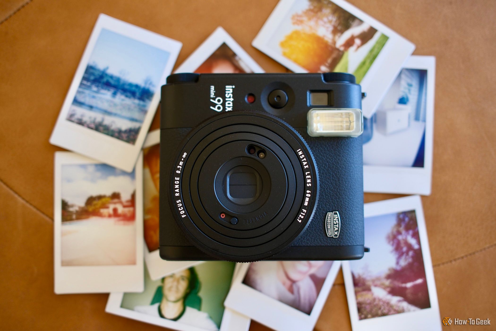 Fujifilm Instax Mini 99 camera laying on top of instant photos