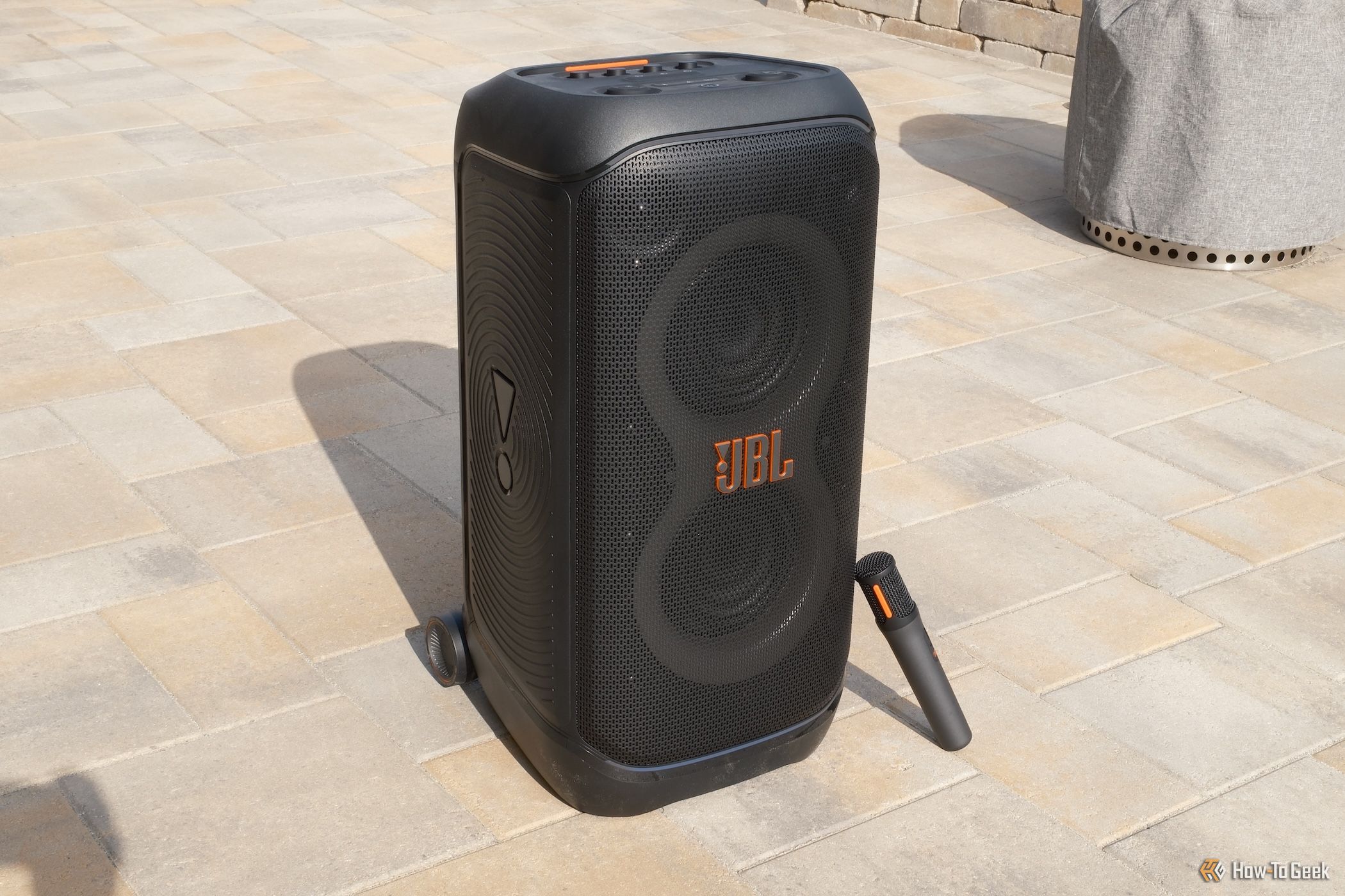 JBL PartyBox Stage 320 outside with a microphone leaning against it