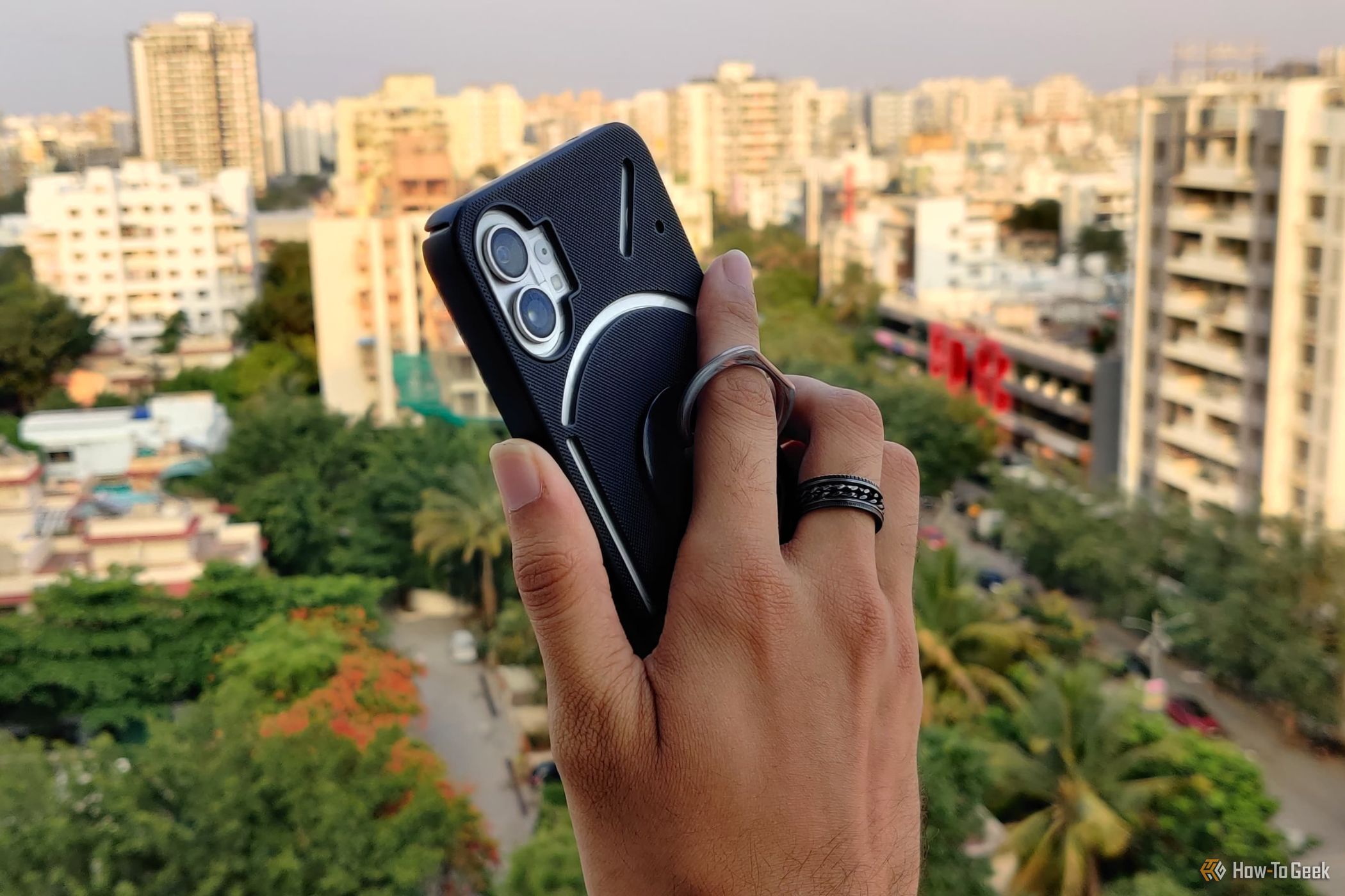 Holding a phone with a ring holder, with a city view in the background.