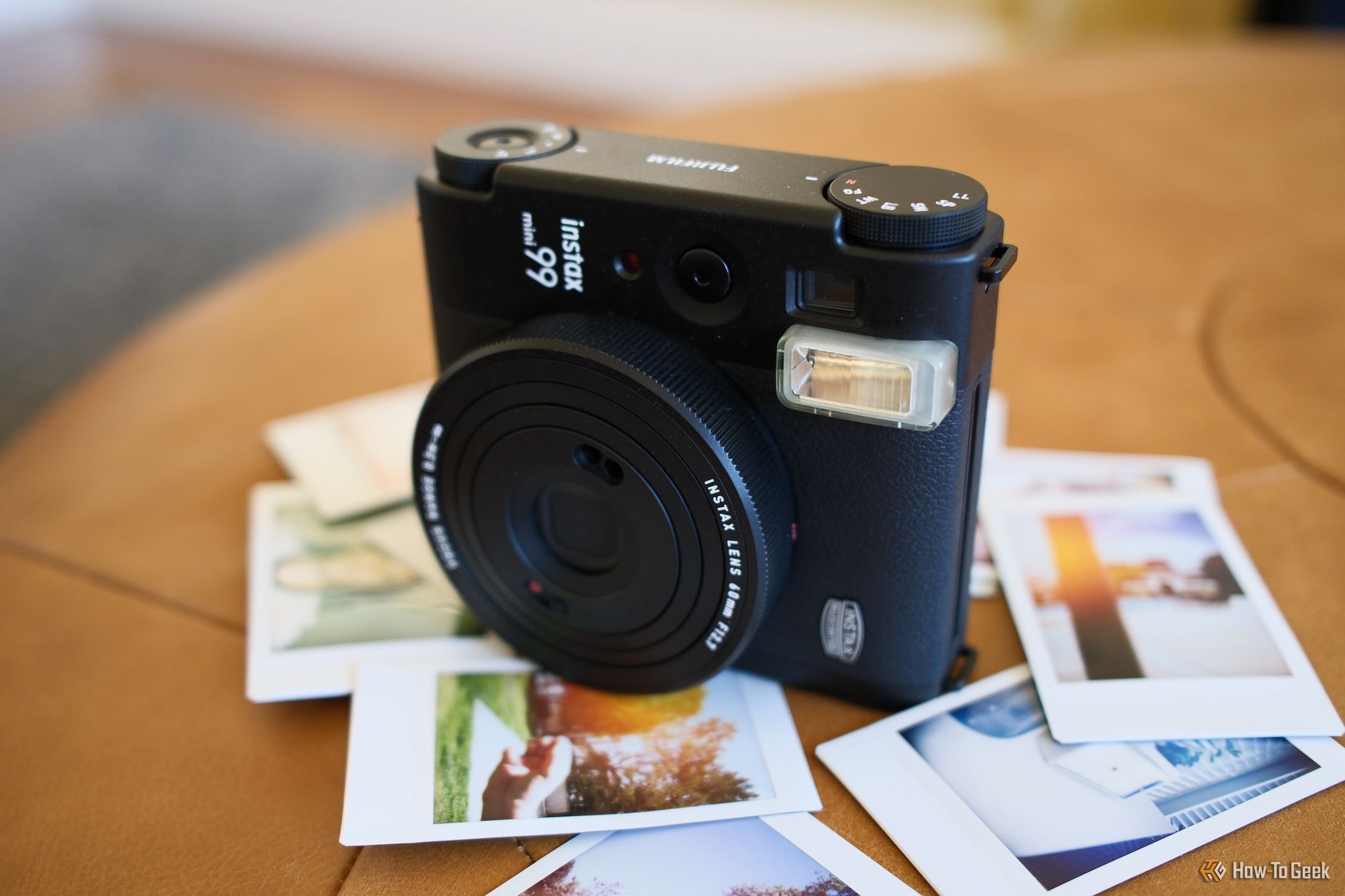 Side view of the Fujifilm Instax Mini 99 with photos underneath