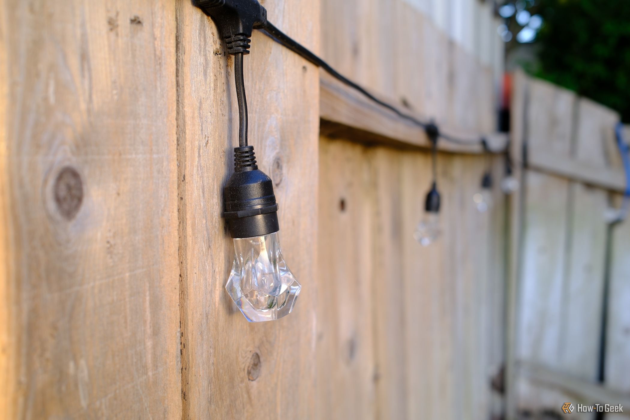 Nanoleaf Essentials Matter Outdoor String Lights hung on a fence