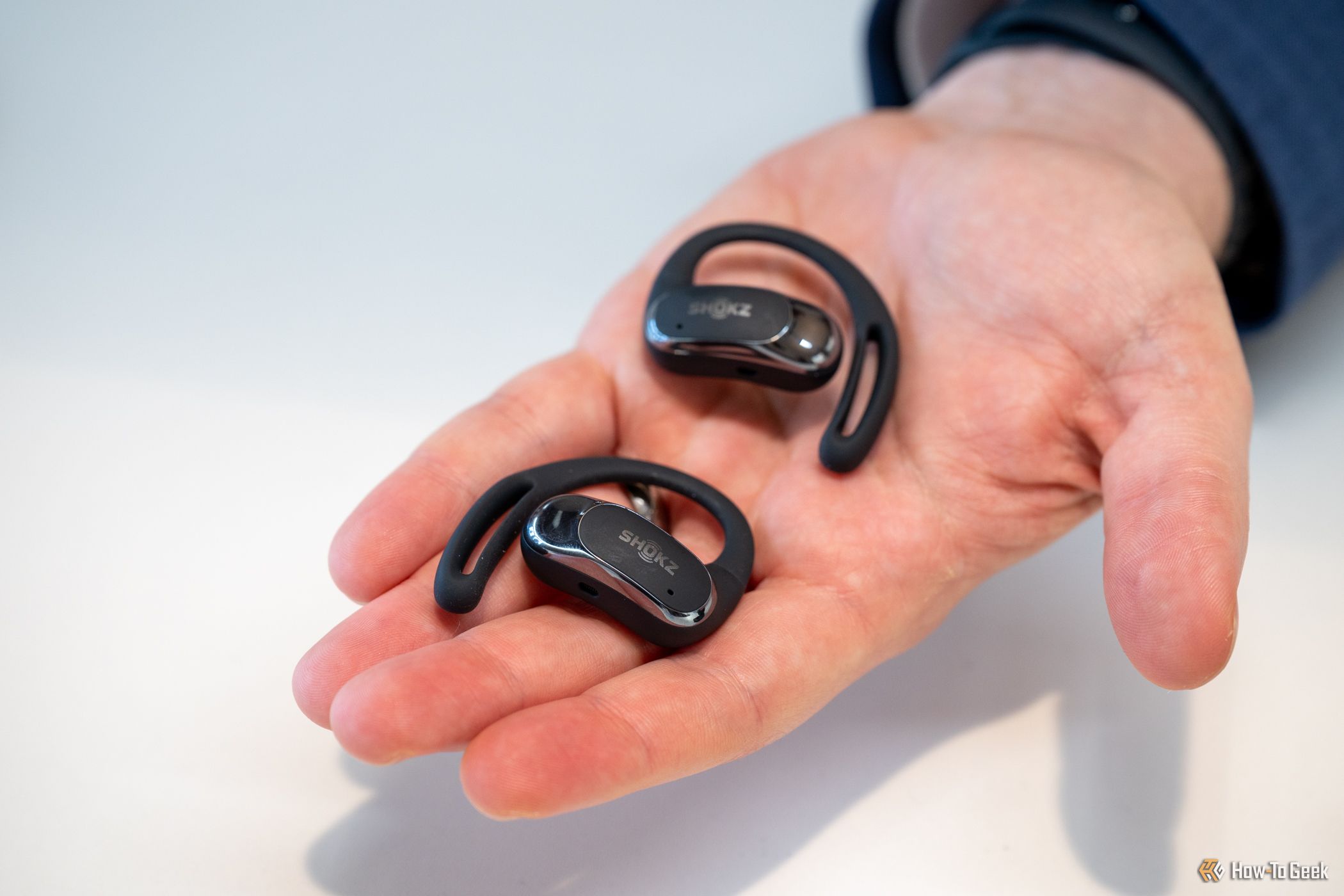 Person holding the Shokz OpenFit Air earbuds