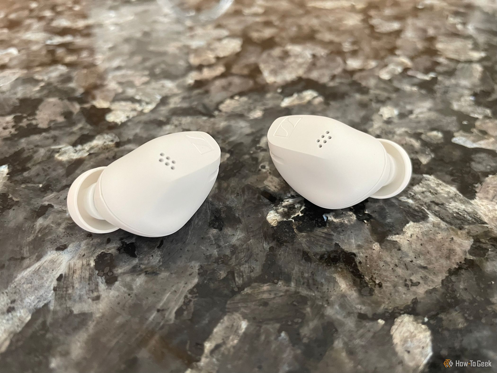 The Sennheiser Accentum True Wireless earbuds on a countertop.