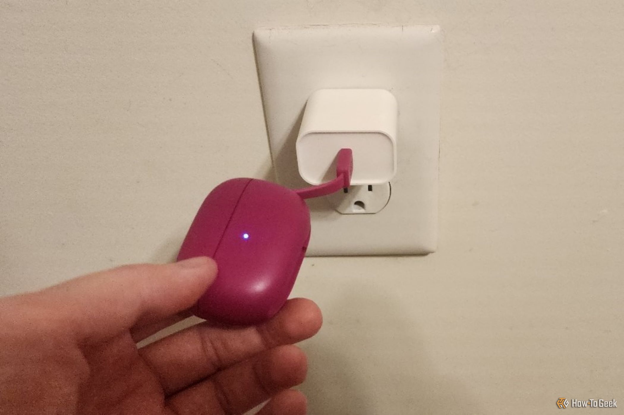 The JLab Go Pop ANC earbud case plugged into a wall charger.