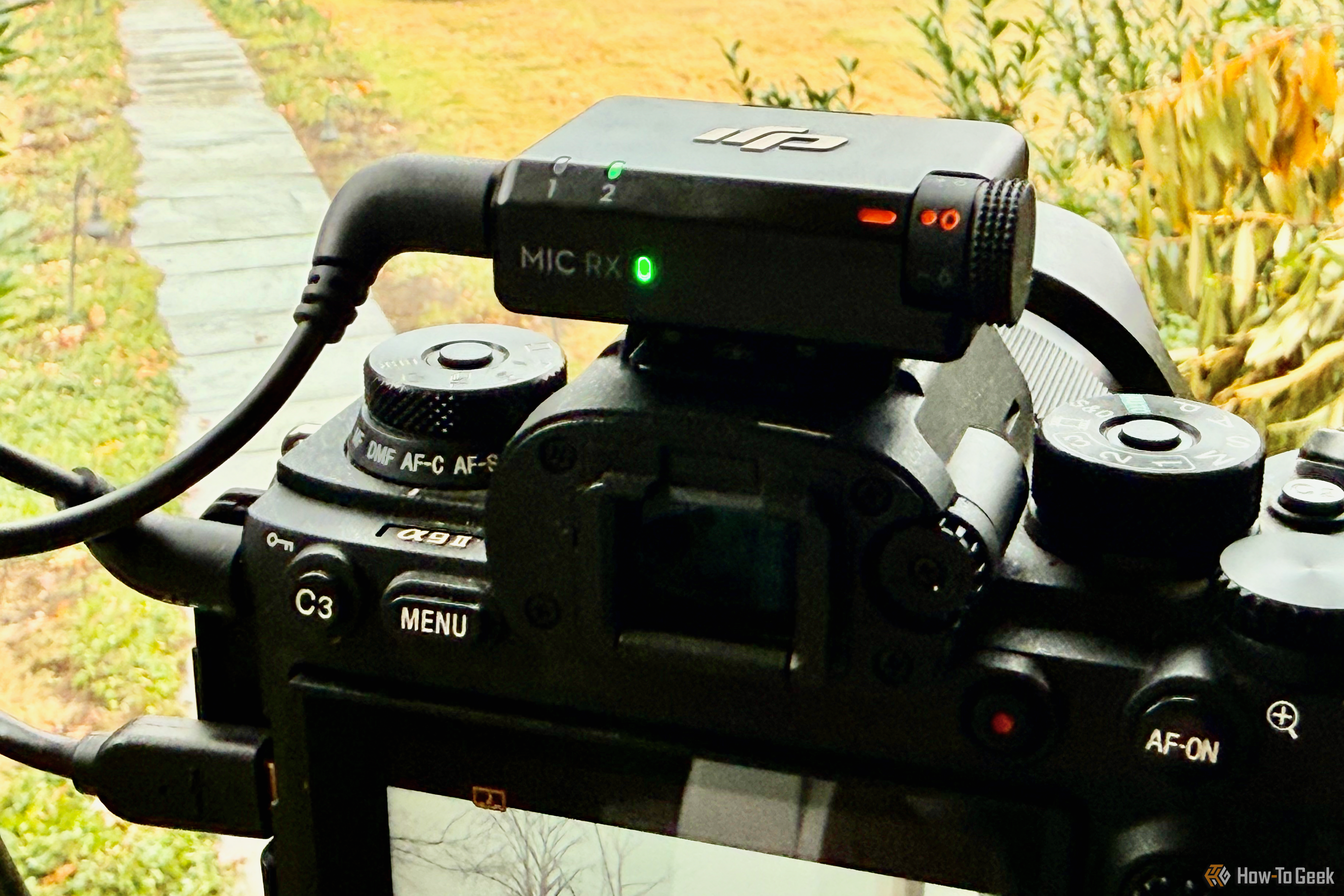 The receiver of the DJI Mic Mini sitting atop a camera. A 3.5" audio jach runs to the side of the camera. 