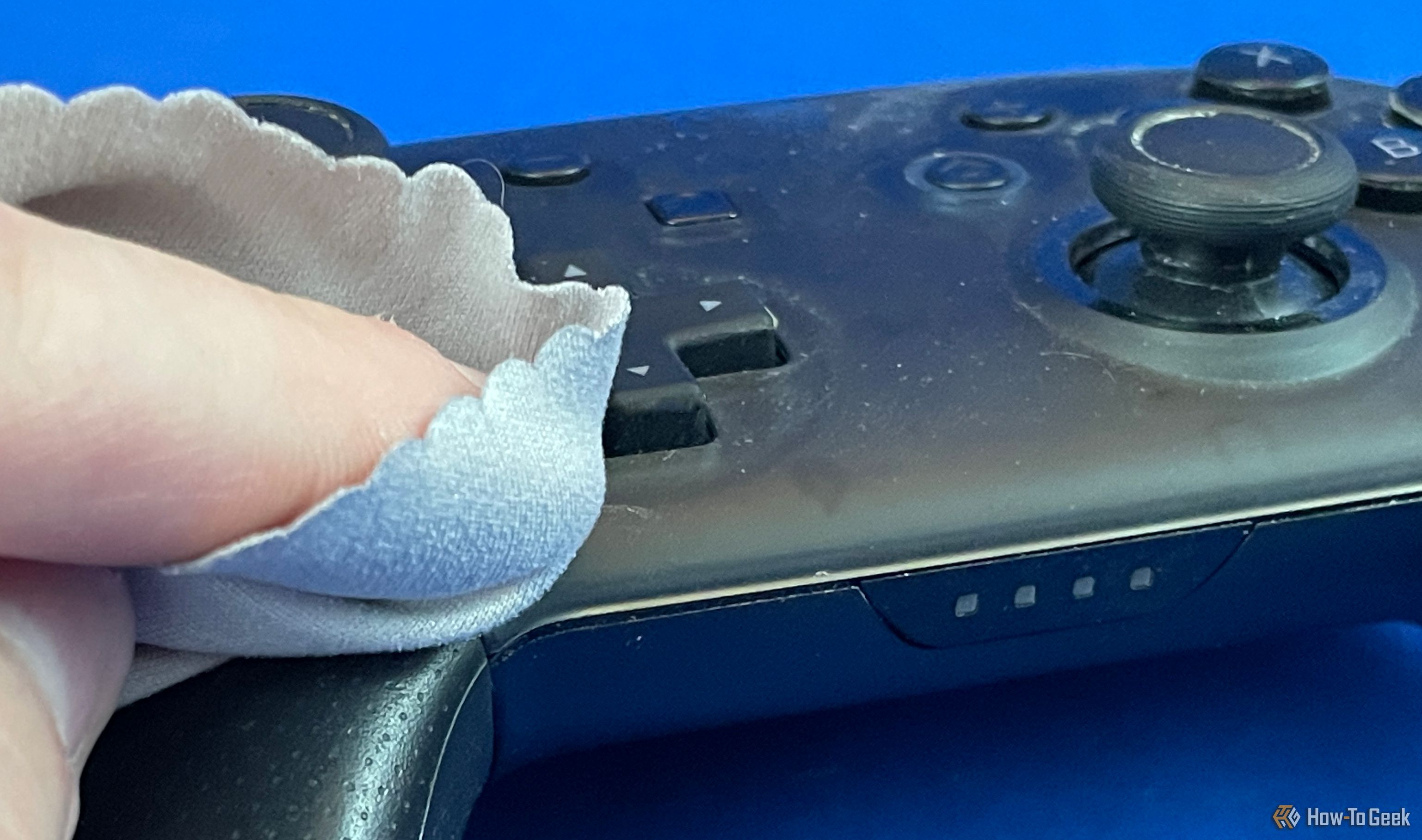 Using a microfiber cloth to clean a Switch Pro Controller.