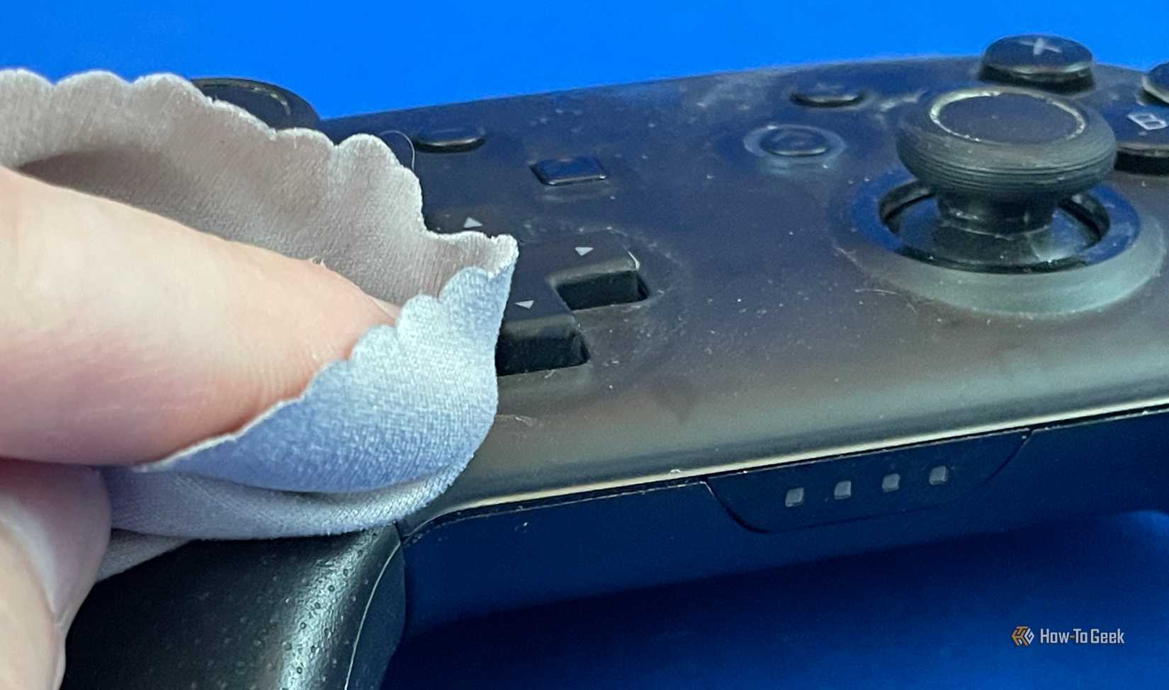 Using a microfiber cloth to clean a Switch Pro Controller.