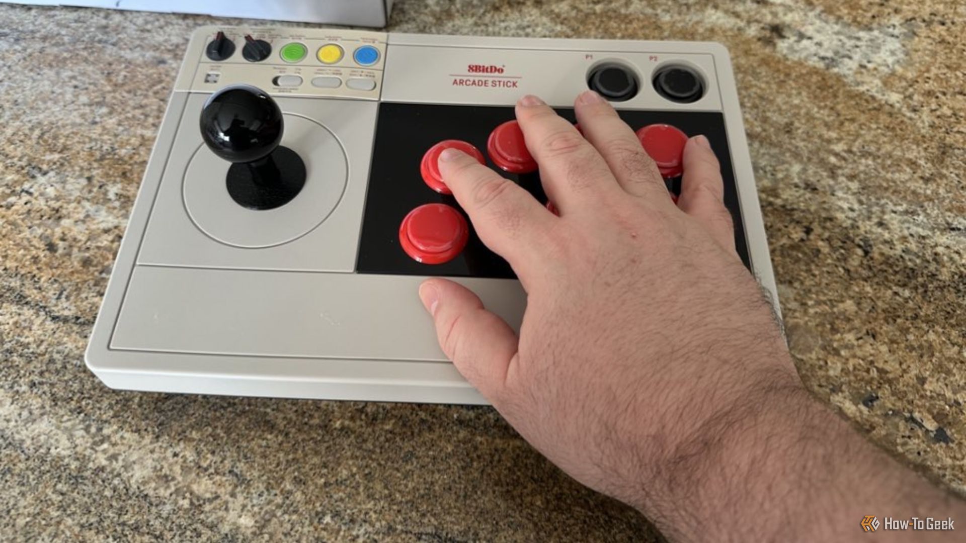 The 8BitDo Arcade Stick for Switch with a hand for scale.