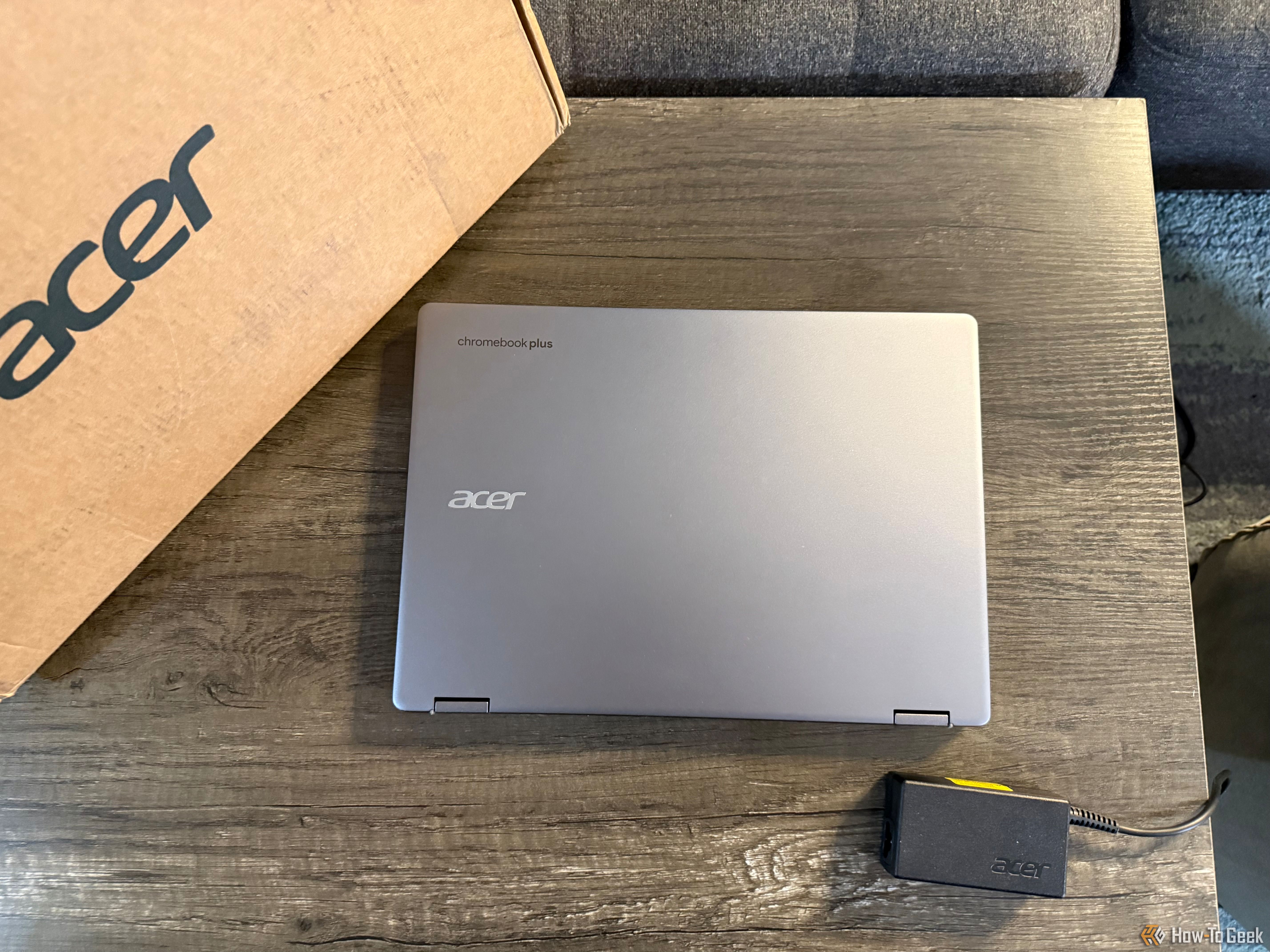 The Acer Chromebook Plus Spin 514 2-in-1 laptop closed on a table with its box and power adapter.