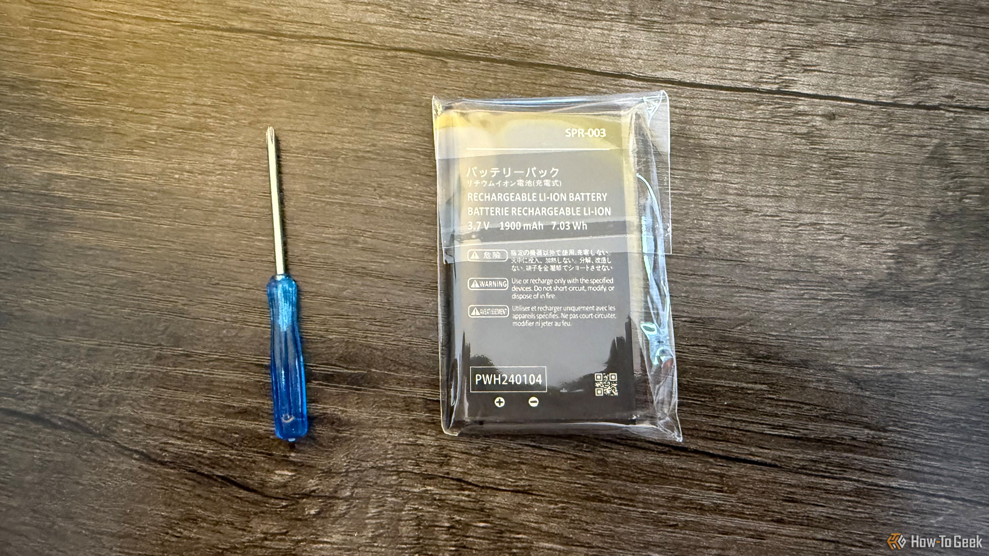 A Nintendo 3DS replacement battery in a plastic case next to a screwdriver.