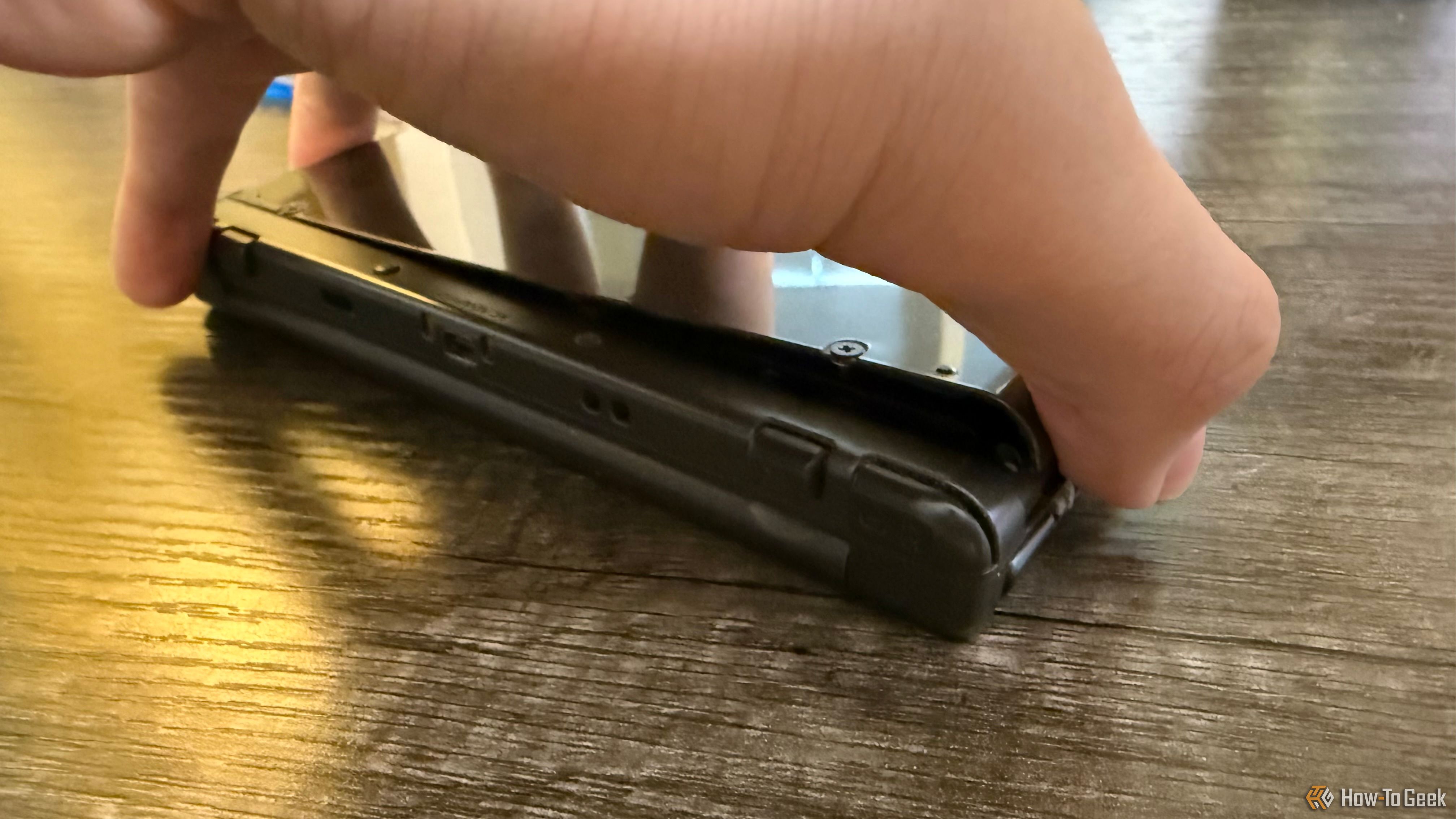 A hand removing the back plate of a New Nintendo 3DS XL.