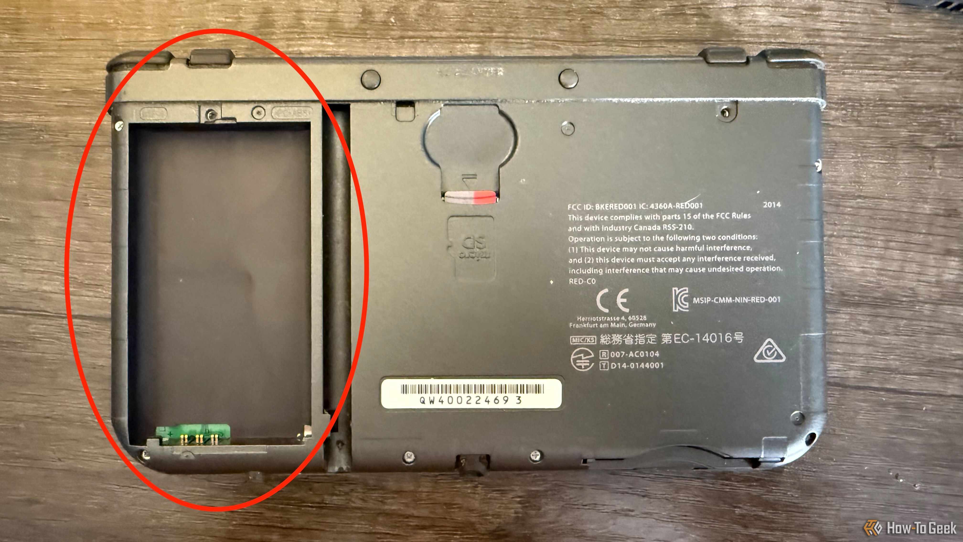 The side of the back of the New Nintendo 3DS XL with a microSD card and a circle around an empty battery slot.