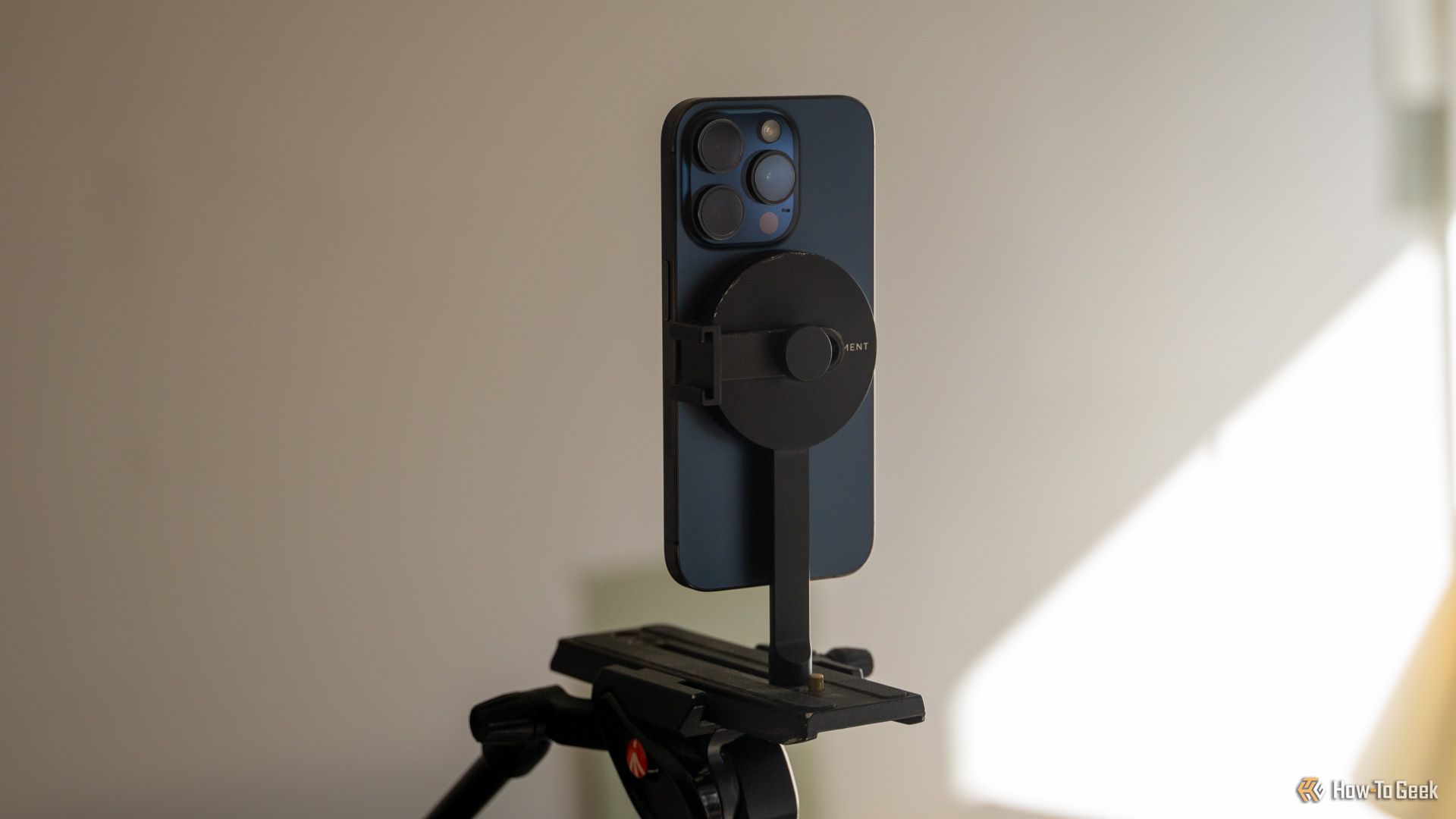 An iPhone 15 Pro mounted vertically on the Moment MagSafe Tripod mount.