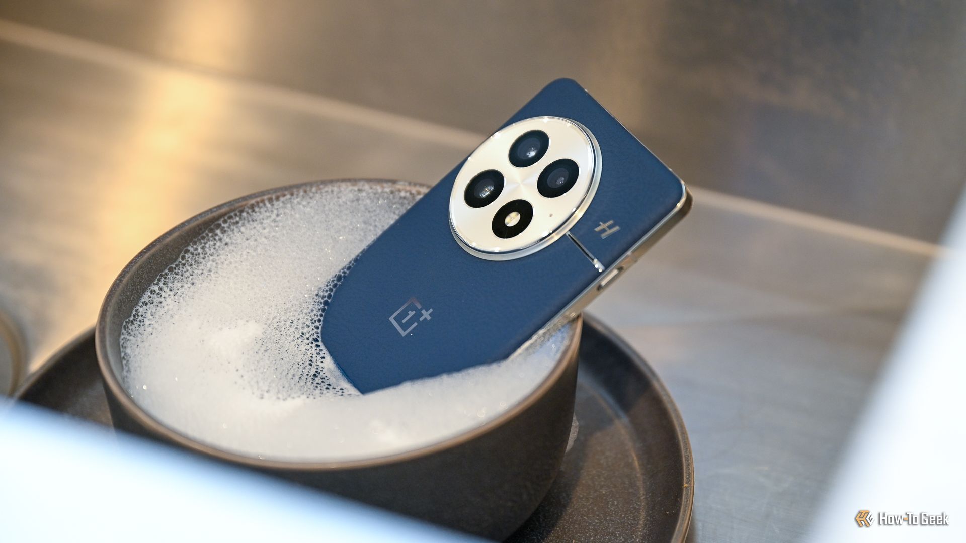 OnePlus 13 seated in a bowl of soapy water.