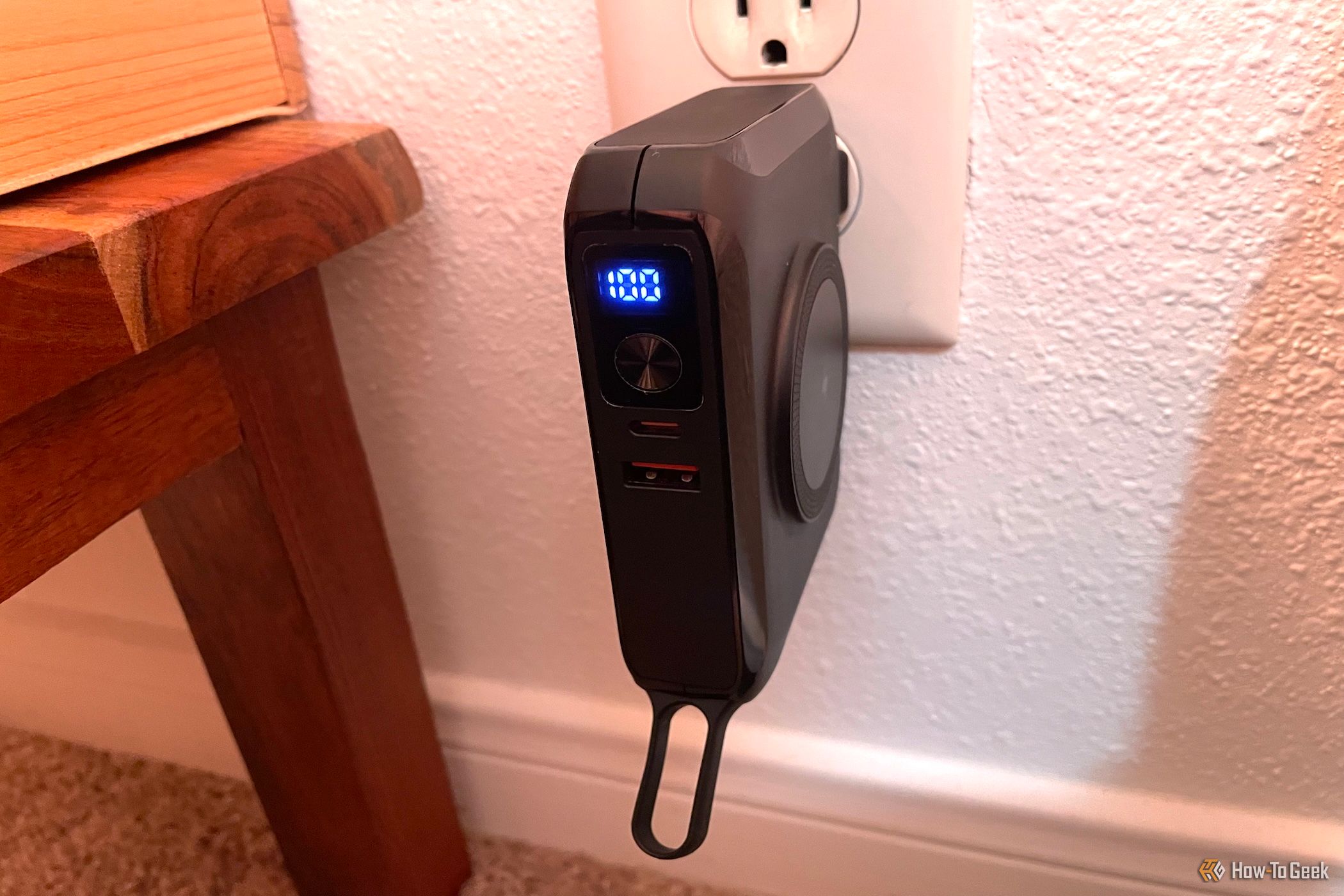 The Raycon 5-in-1 Magic Laptop Power Bank plugged into a wall outlet.