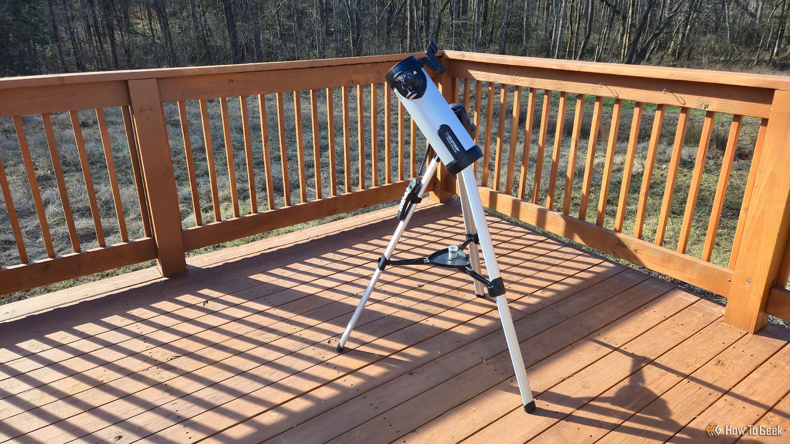 A Celestron 114LCM telescope sitting on a deck.