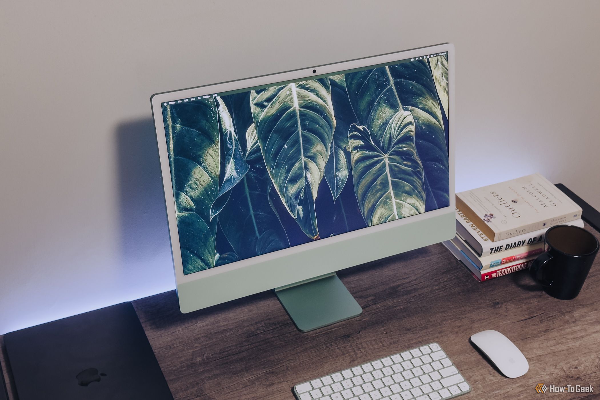 Green M4 iMac display from an upward angle on wooden desk.