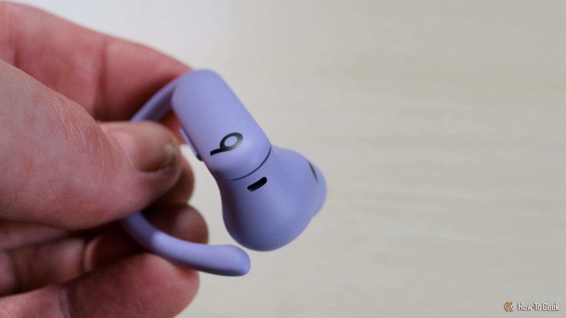 Holding one of the Beats PowerBeats Pro 2 earbuds.