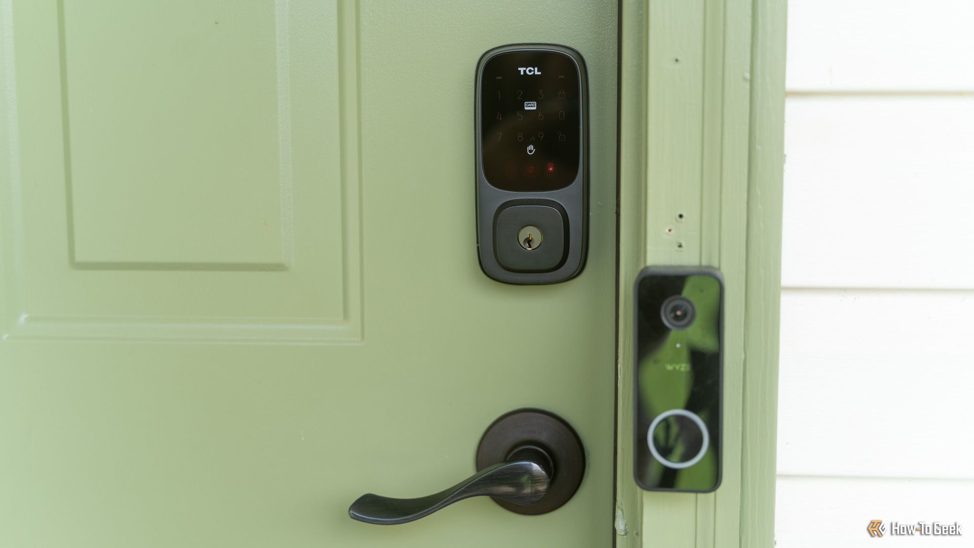 The TCL D1 Pro palm vein smart lock installed on a green door.