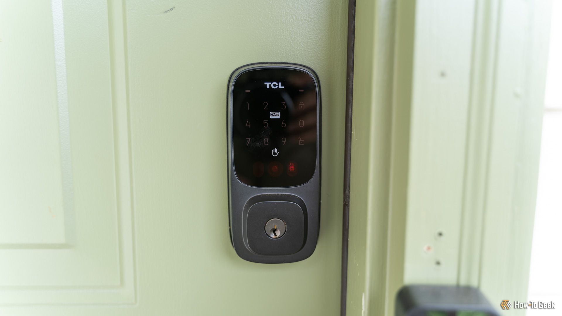 A front close up shot of the TCL D1 Pro palm vein smart lock installed on a green door.